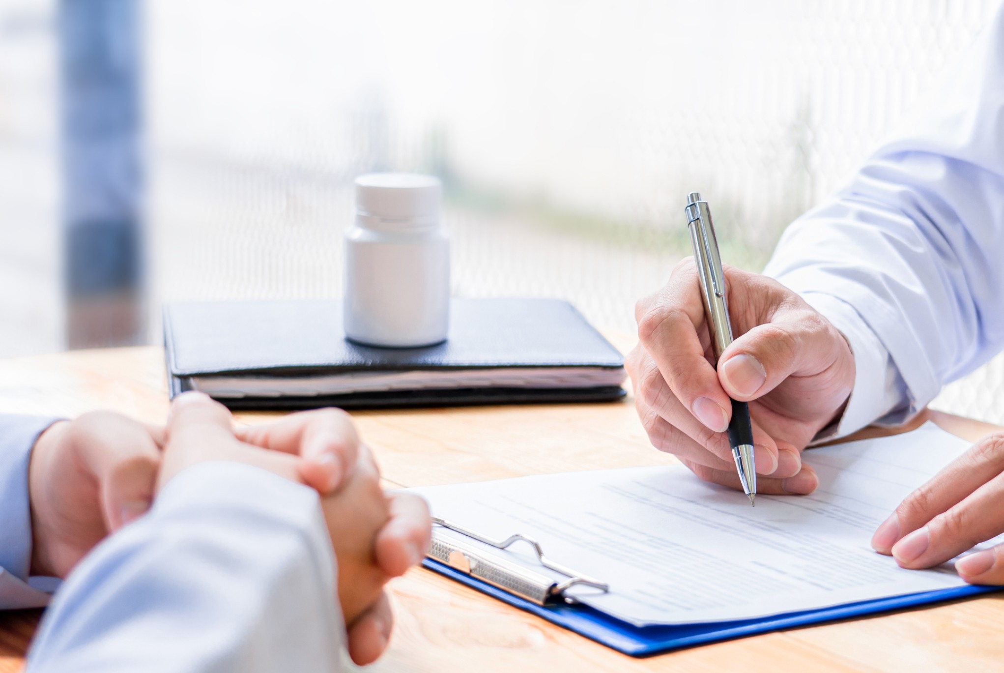 Healthcare professional writing on a clipboard during a consultation, representing efficient management of the healthcare revenue cycle.