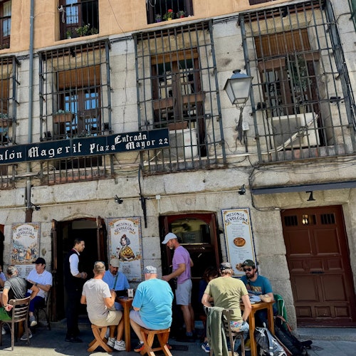 Lokalno stanovništvo i turisti objeduju ispred šarmantnog restorana smještenog pod kamenim zgradama u blizini trga Plaza Mayor.
