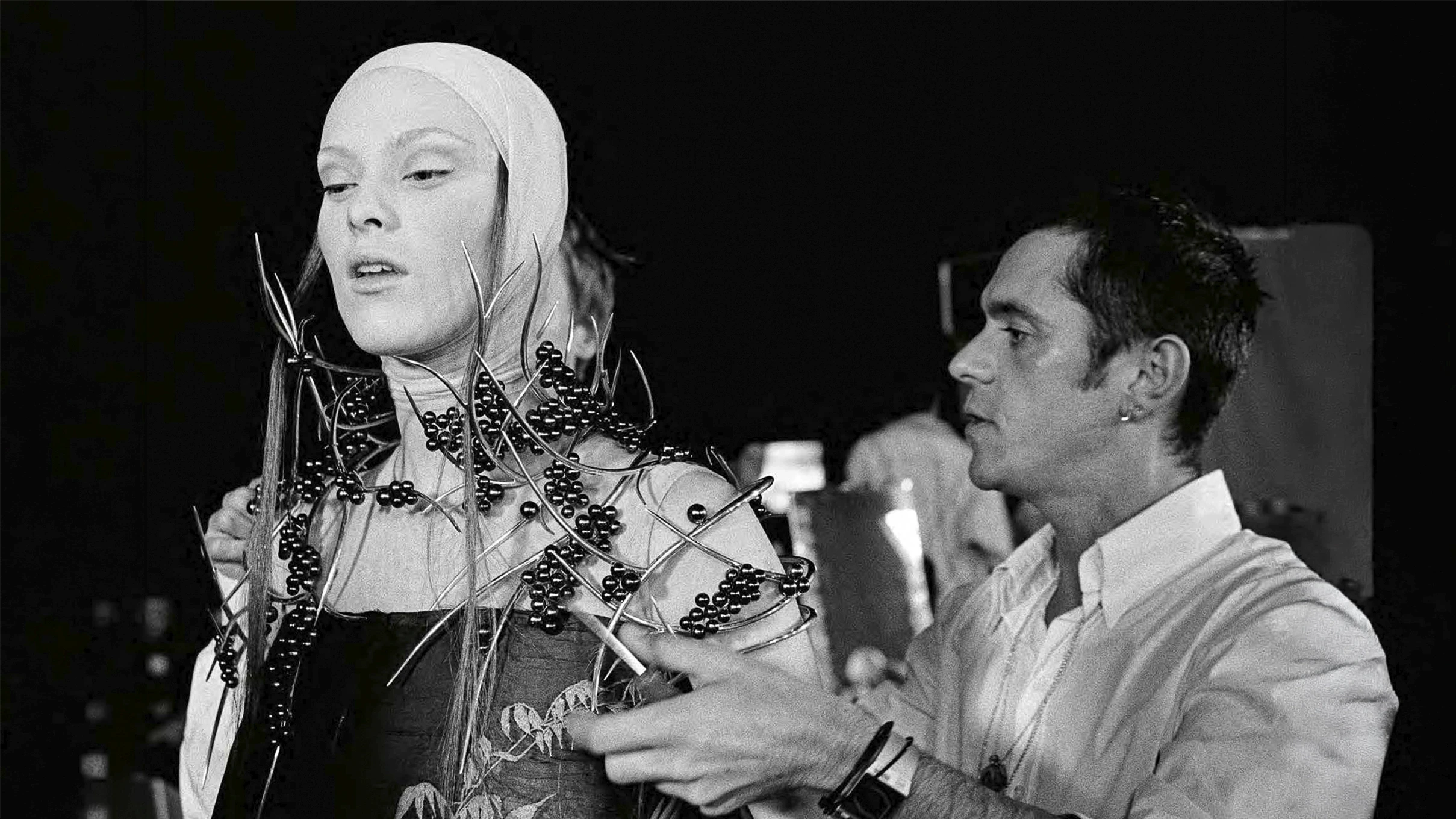 Backstage archival photo of a model wearing an intricate shoulder piece made of silver thorns and freshwater pearls, created by Shaun Leane for Alexander McQueen's VOSS show.