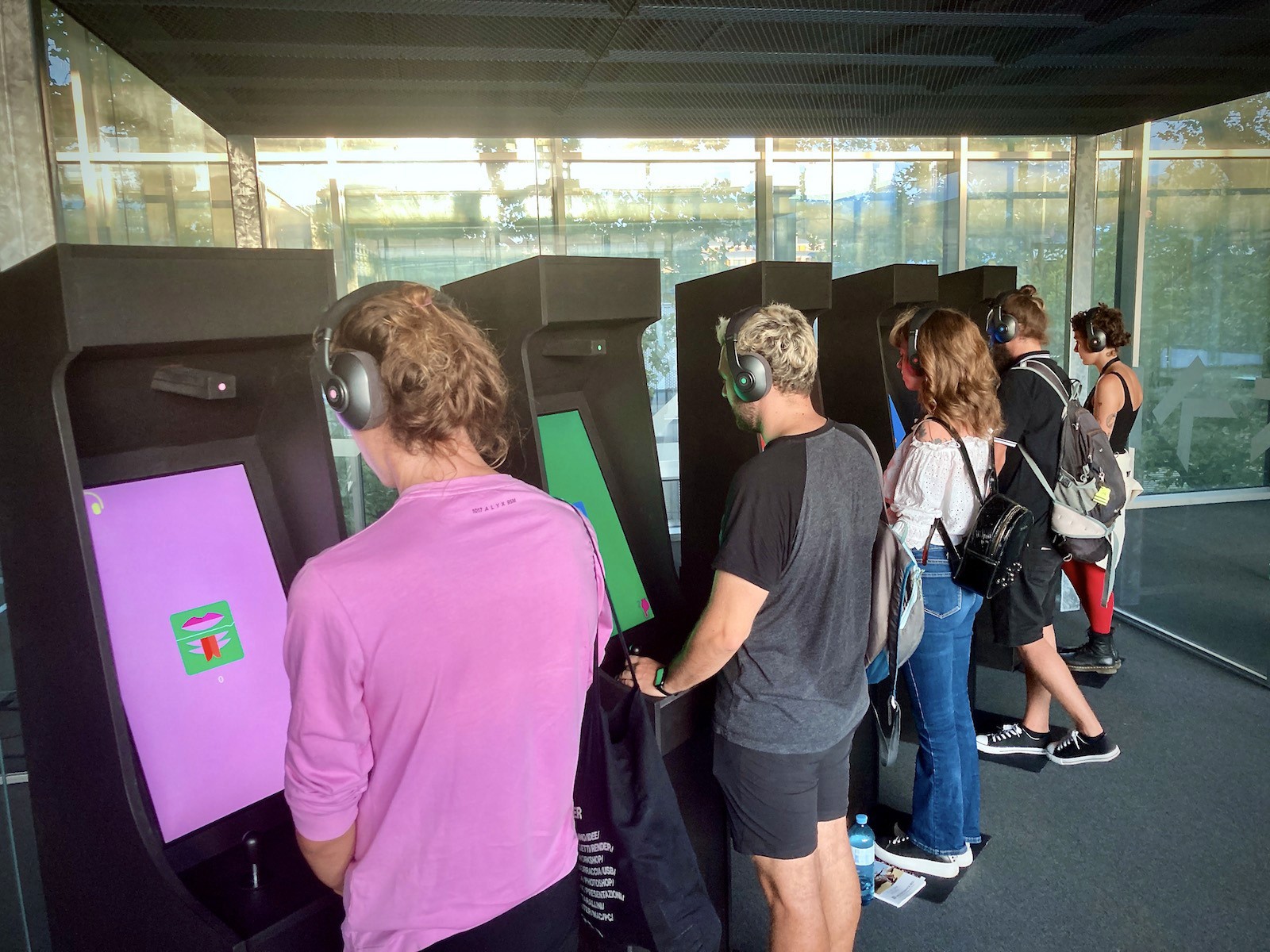 People wearing headphones play arcade games.