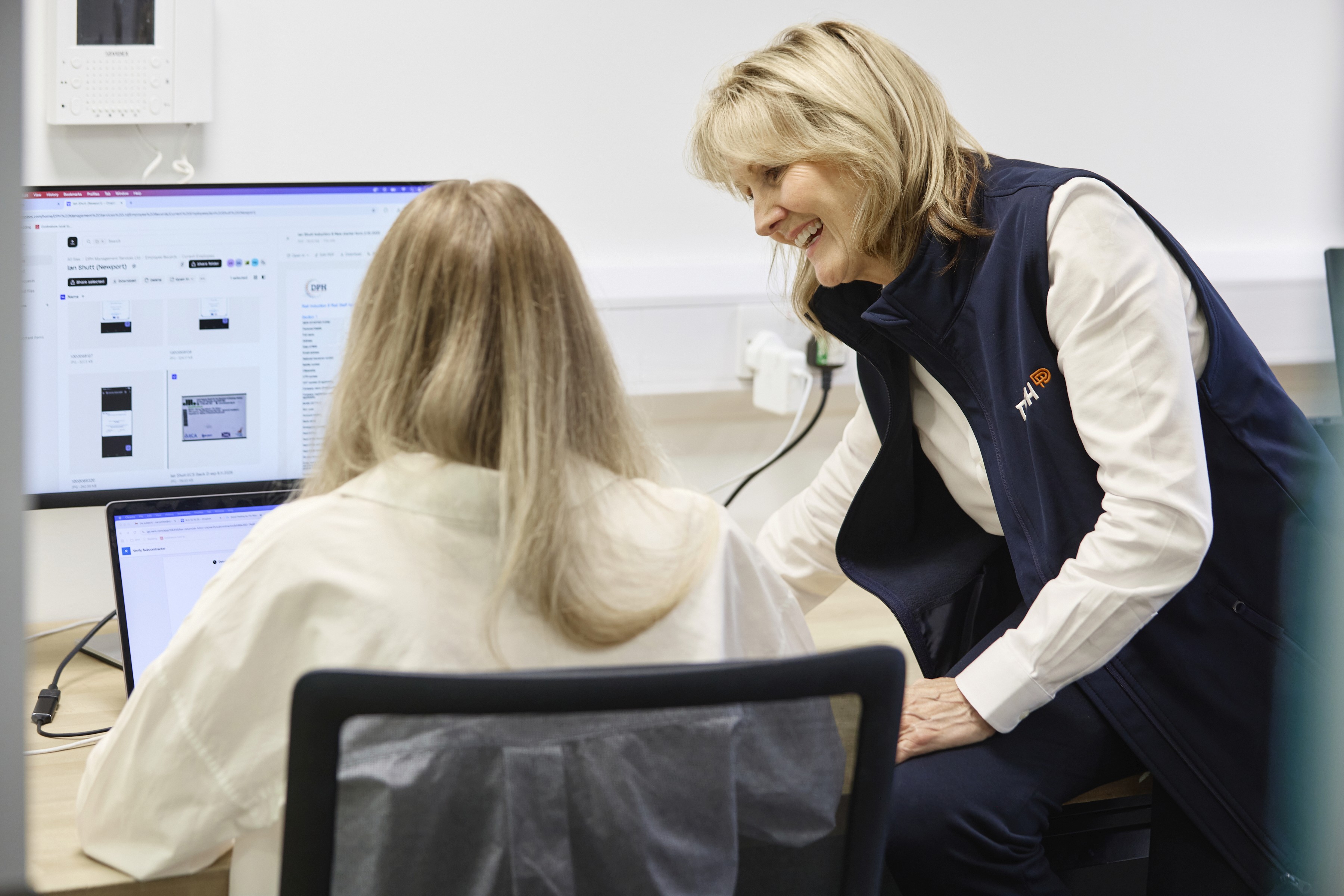 Modern glass building with illuminated interior and reflections at sunset