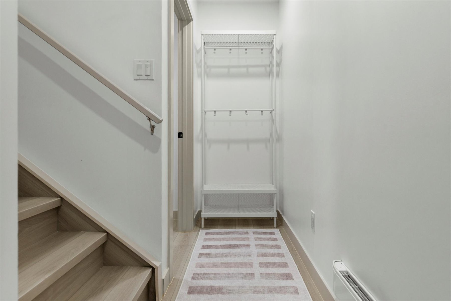 Legal suite entry after: finished stair, white walls and a built-in coat rack