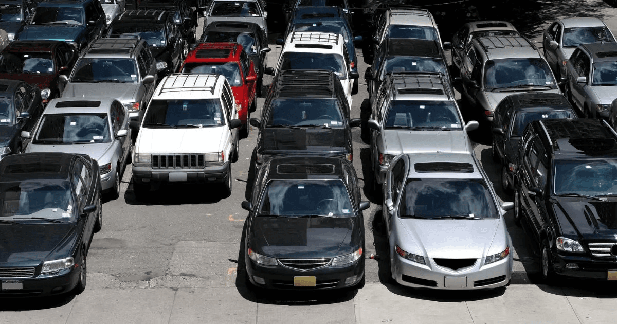 Rows of cars fill a crowded outdoor parking lot.