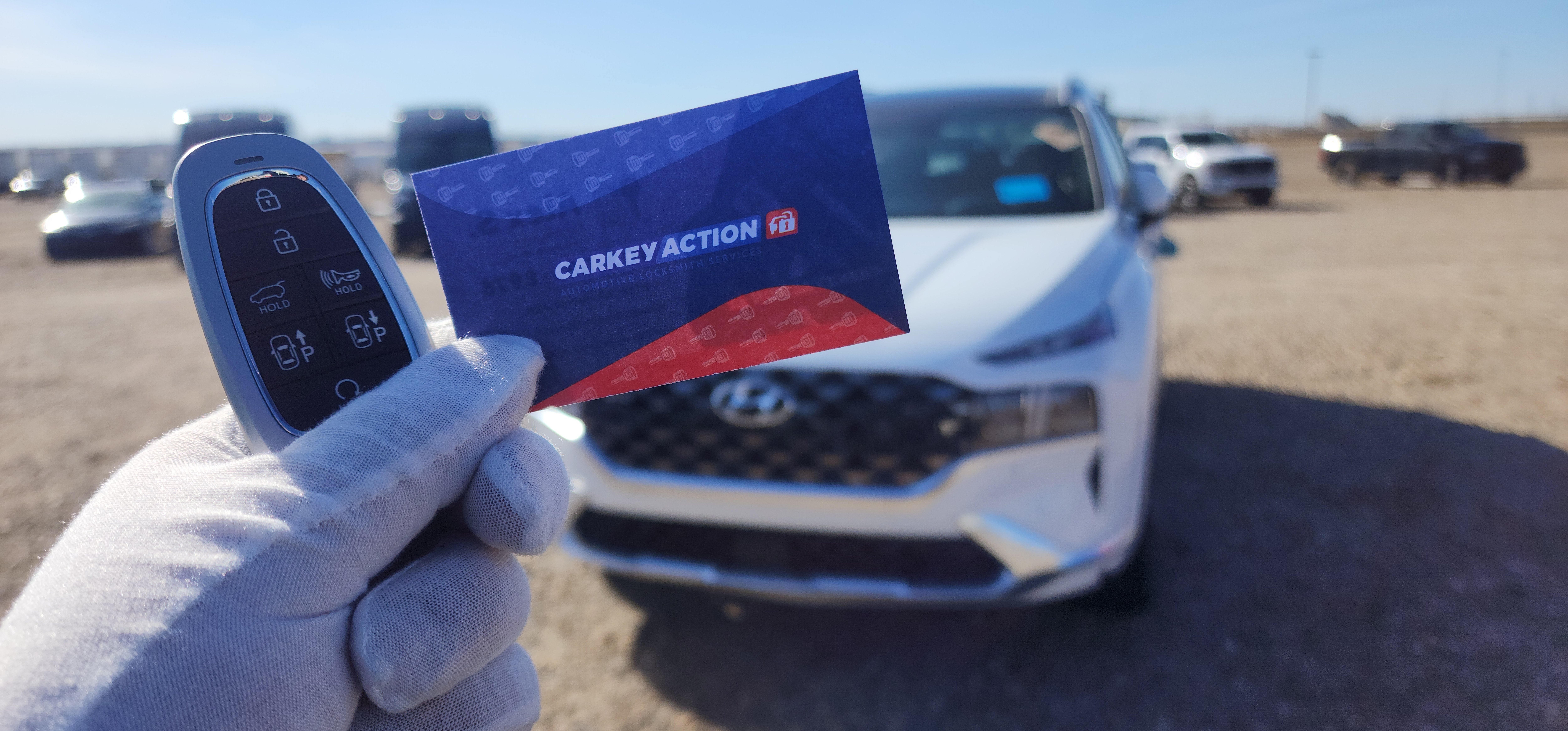 CarKeyAction business card and car key held in front of a Hyundai vehicle after car key replacement service