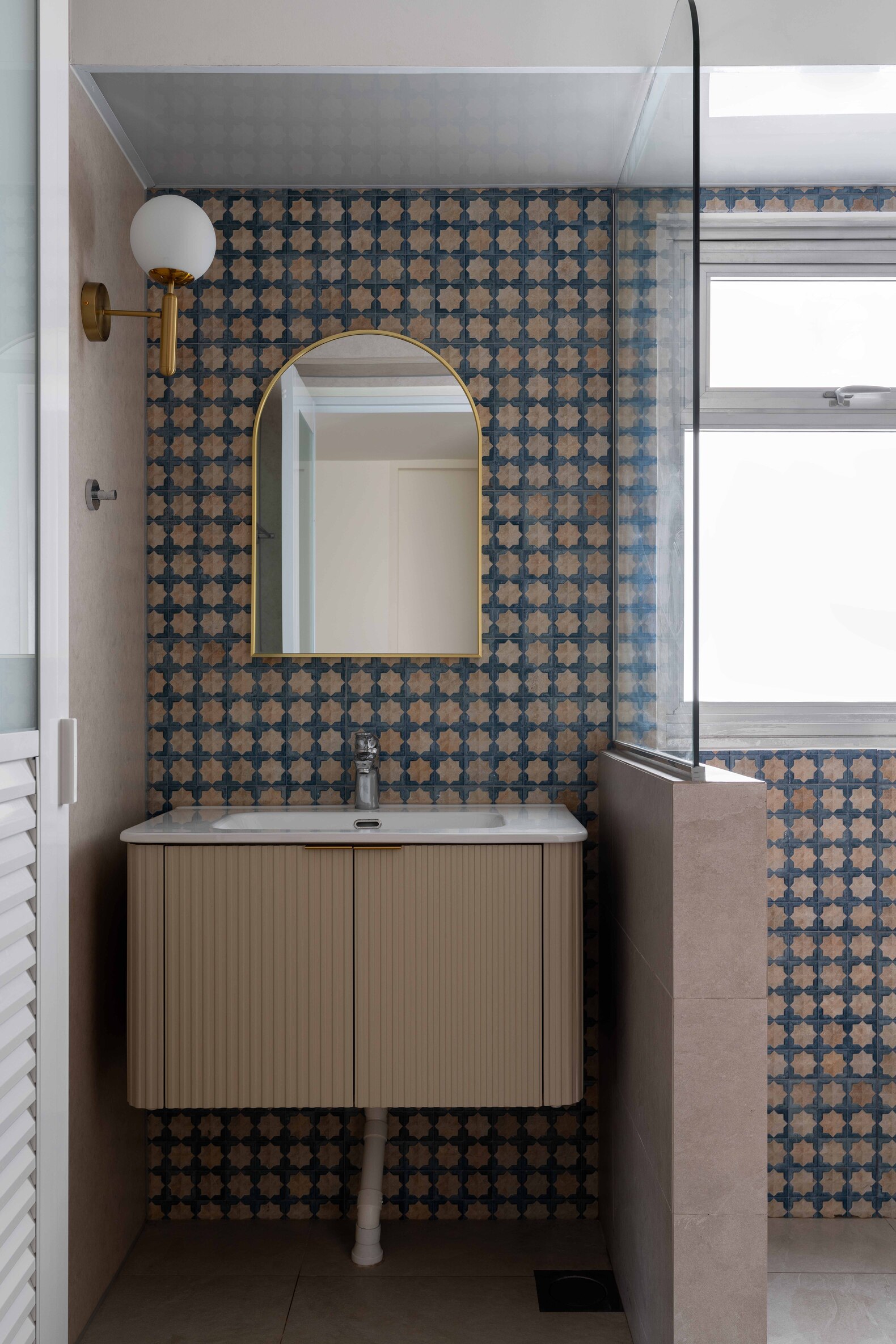 A modern bathroom featuring a minimalist sink, a mirror, and neutral-toned walls and cabinetry. Natural light present.