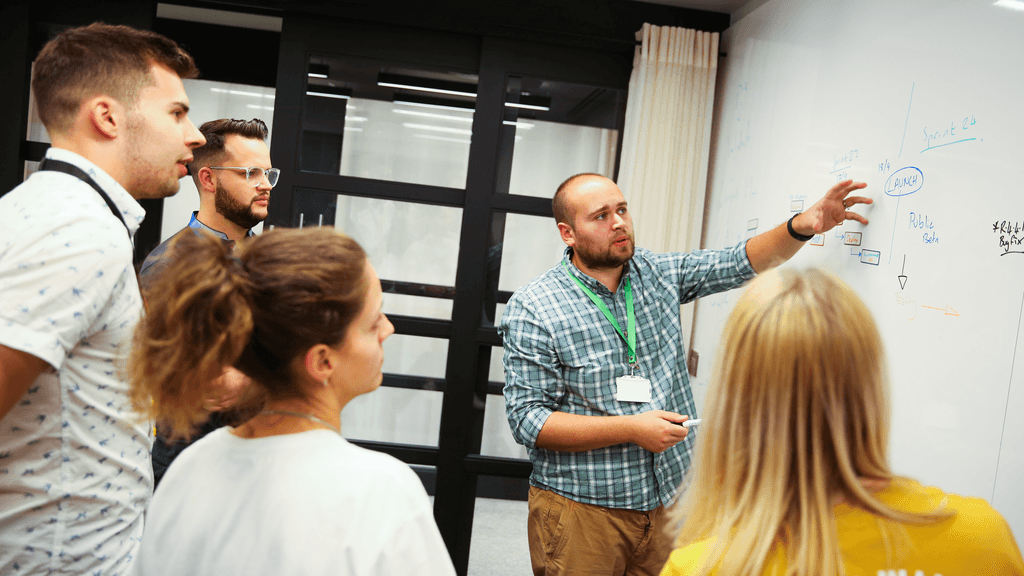 A team brainstorming ideas together in front of a whiteboard, discussing and collaborating on a project.