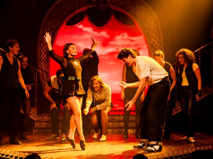 Lead dancer centre stage as the cast cheers in a lively scene from Emerald Storm.