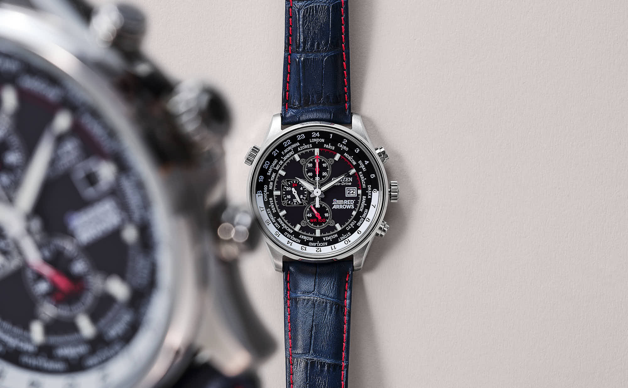 A close-up of two watches: a large chronograph with a dark face and a smaller watch with a simple design.