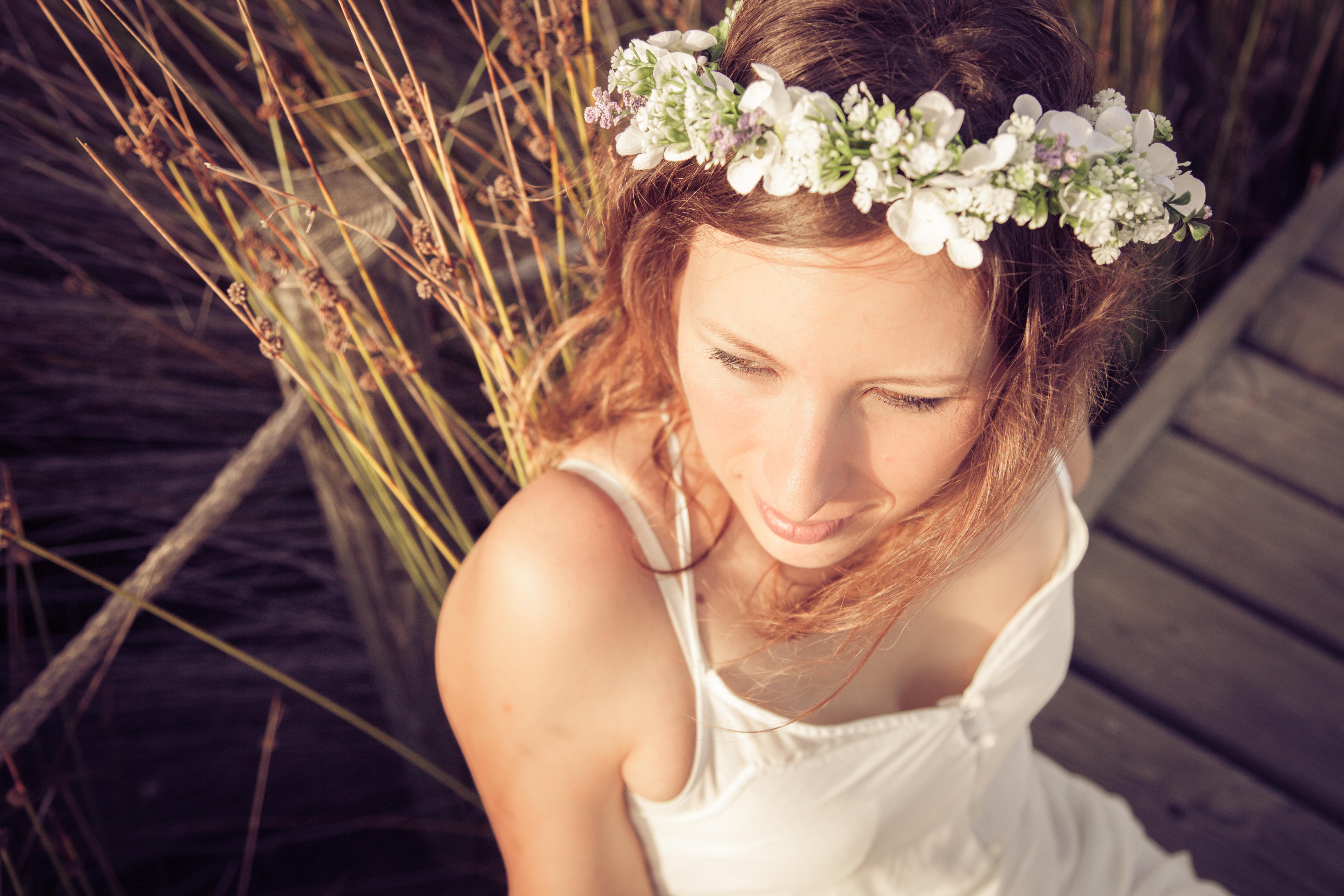 Chica mirando hacia un lado con un vestido blanco y una corona de flores