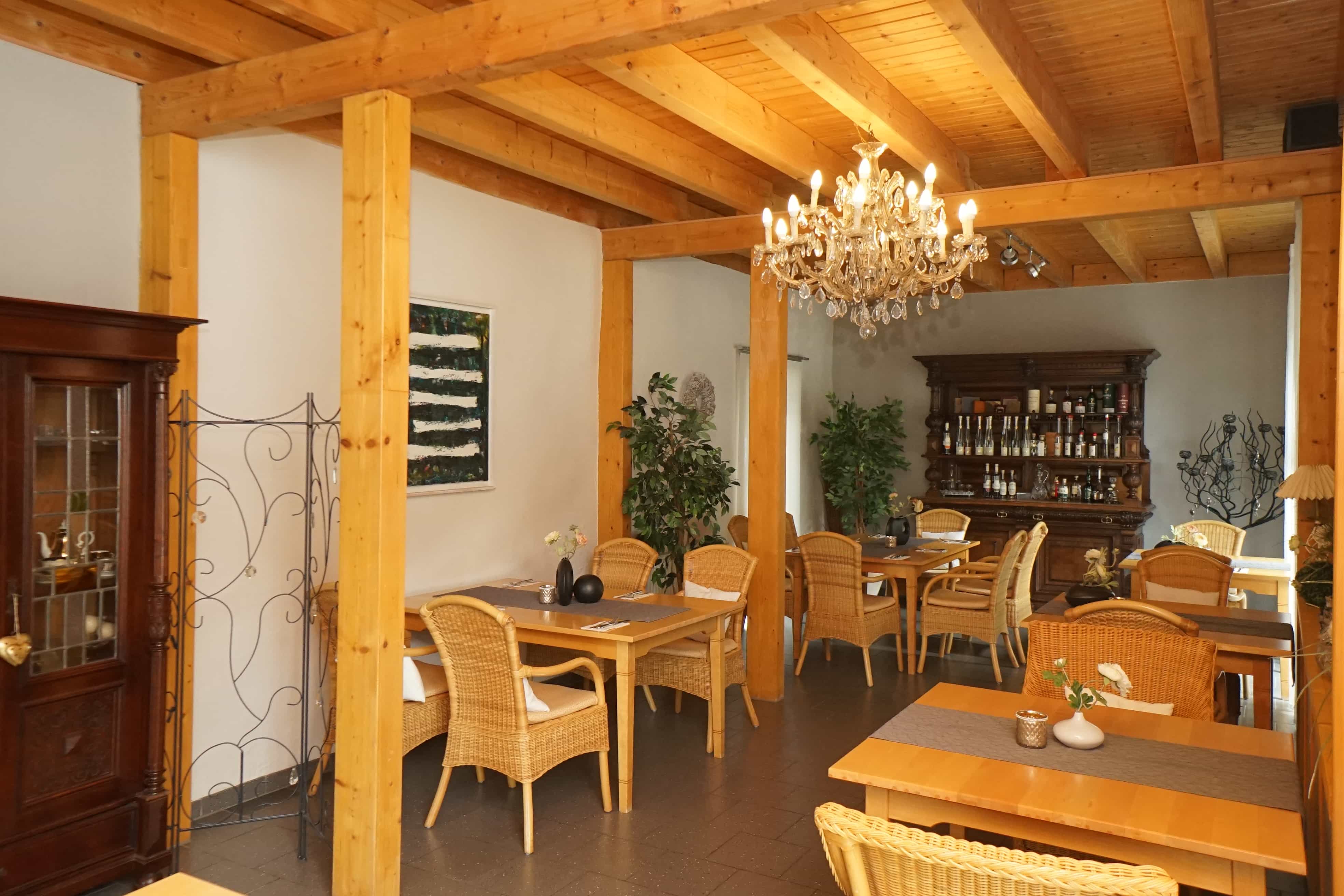 Restaurant with chandelier, wooden tables, and wicker chairs