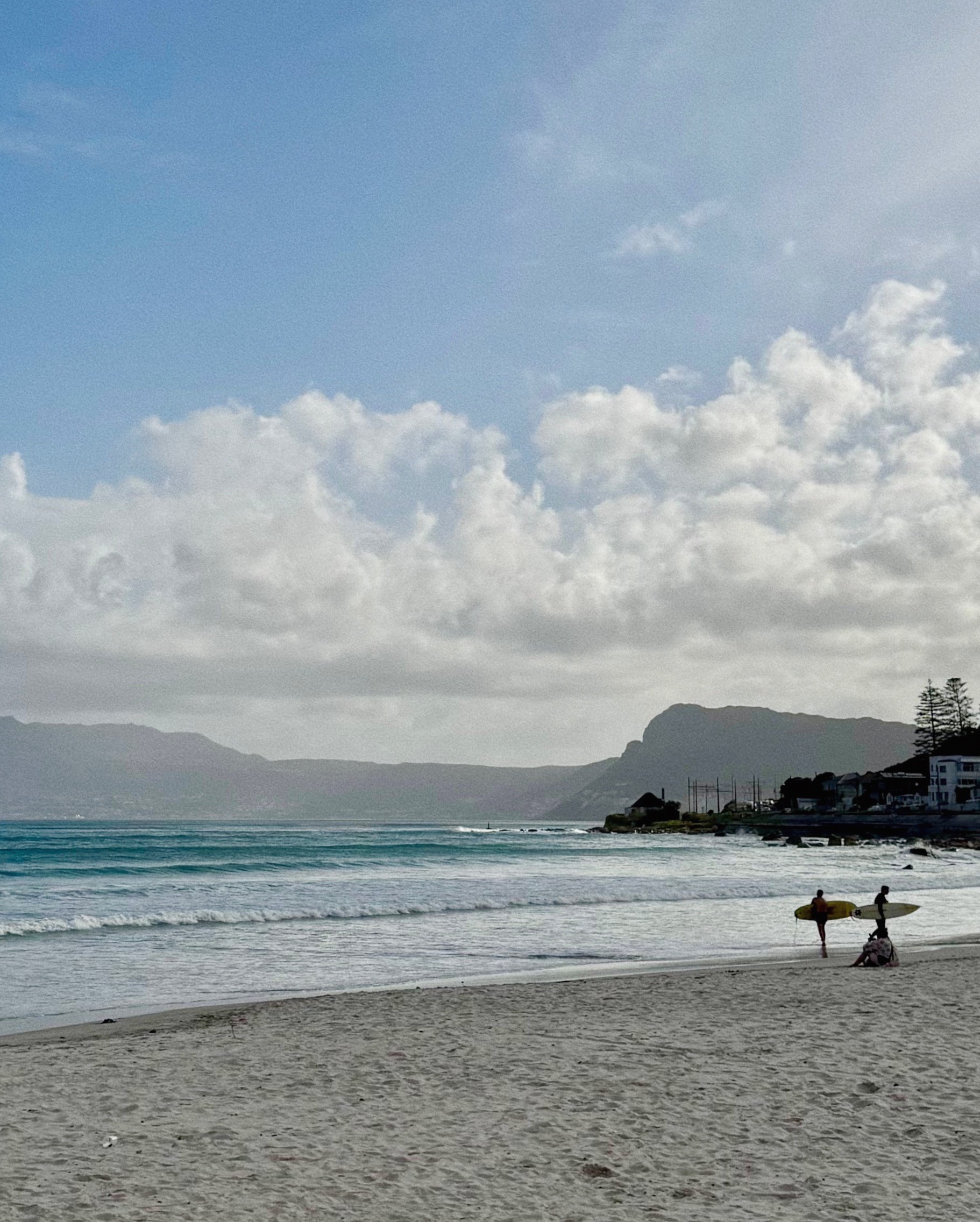 Surfers at Muizenberg beach in Cape Town getting out of the water after their surf session