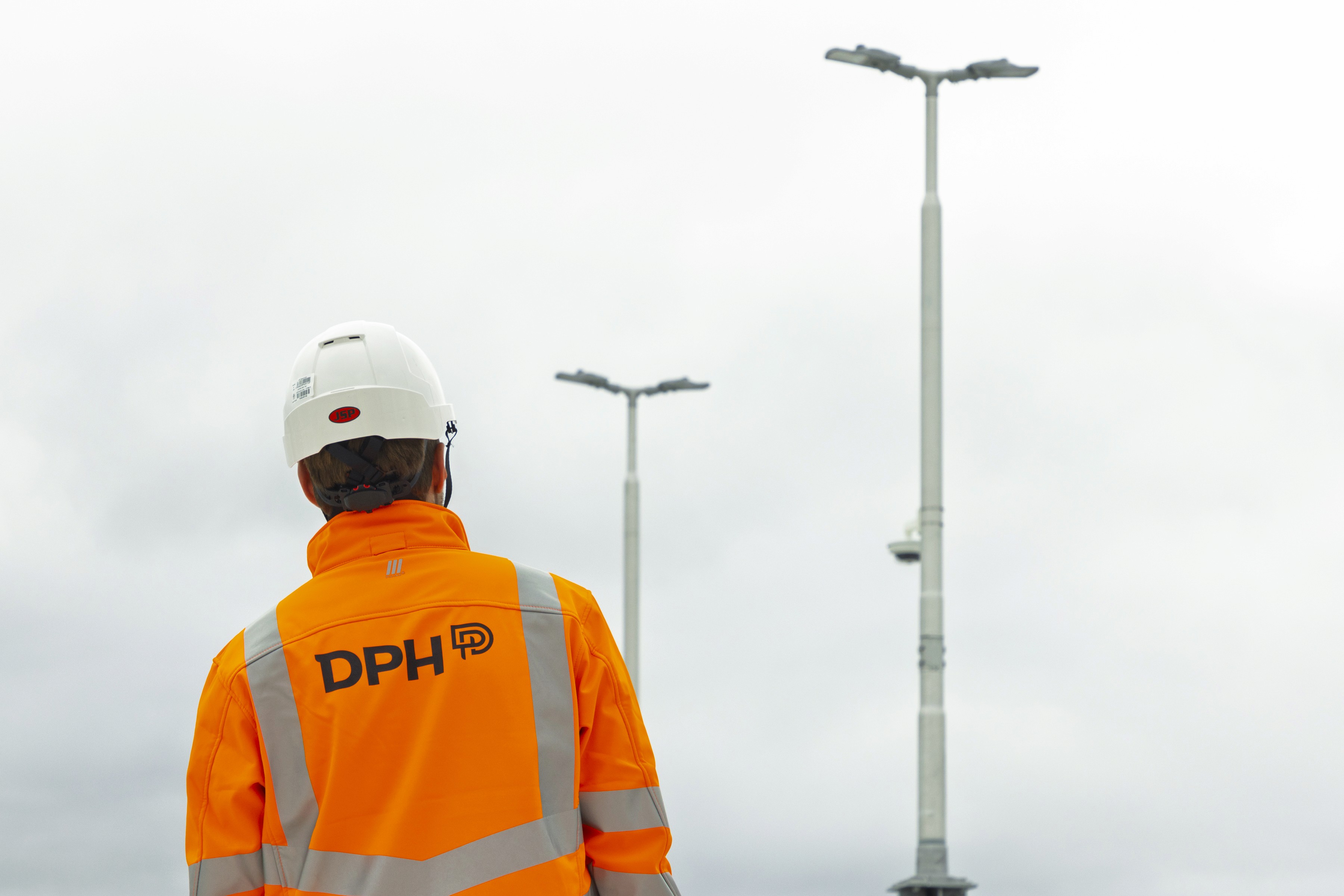 Rooftop garden with trees and plants, overlooking a cityscape at sunset with a tall building in the background