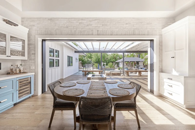 Full view of the living room from angle 2, featuring boho furniture and decor with a view of the backyard through French doors, blending indoor comfort with outdoor beauty. Photo by Todd Huge.