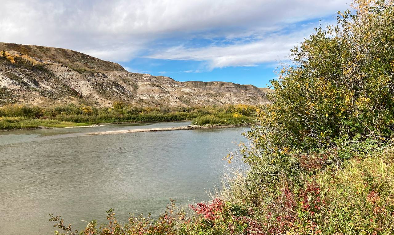 Red Deer River with riparian buffer and exposed badlands terrain along Drumheller flood protection corridor