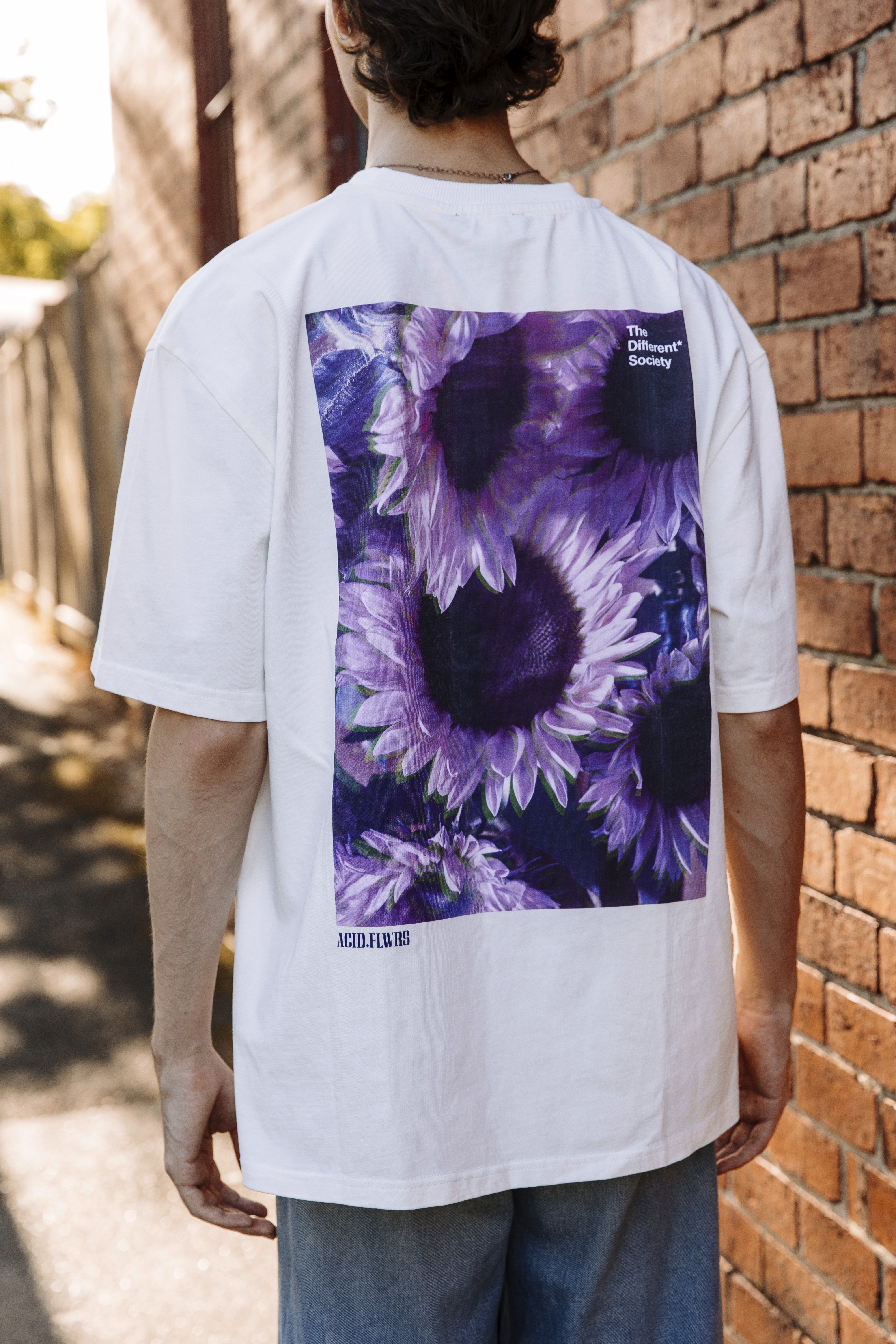 A person wearing the Purple Sunflower t-shirt, with the image on the back on display