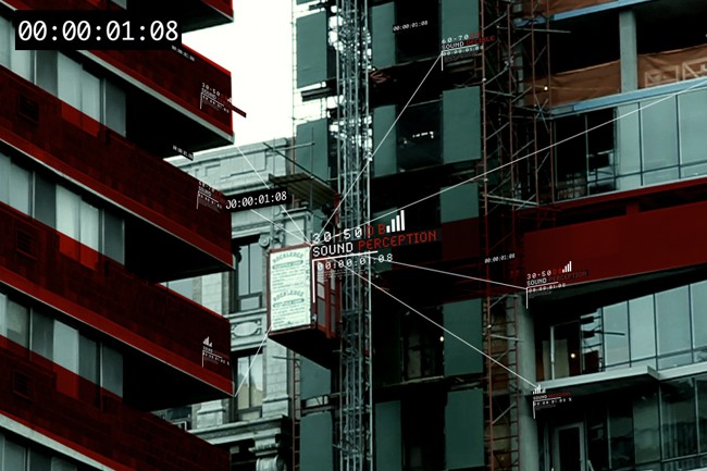 The image shows a tall building with red and white horizontal bands on its facade. Scaffolding is attached to the building, and a sign reading “SOUND PERCEPTION” is visible on a lower level. White lines crisscross the image, likely indicating sound transmission or signal paths. The time stamp “00:00:01:08” appears in the top left corner. The building’s windows reflect the sky and surrounding structures.