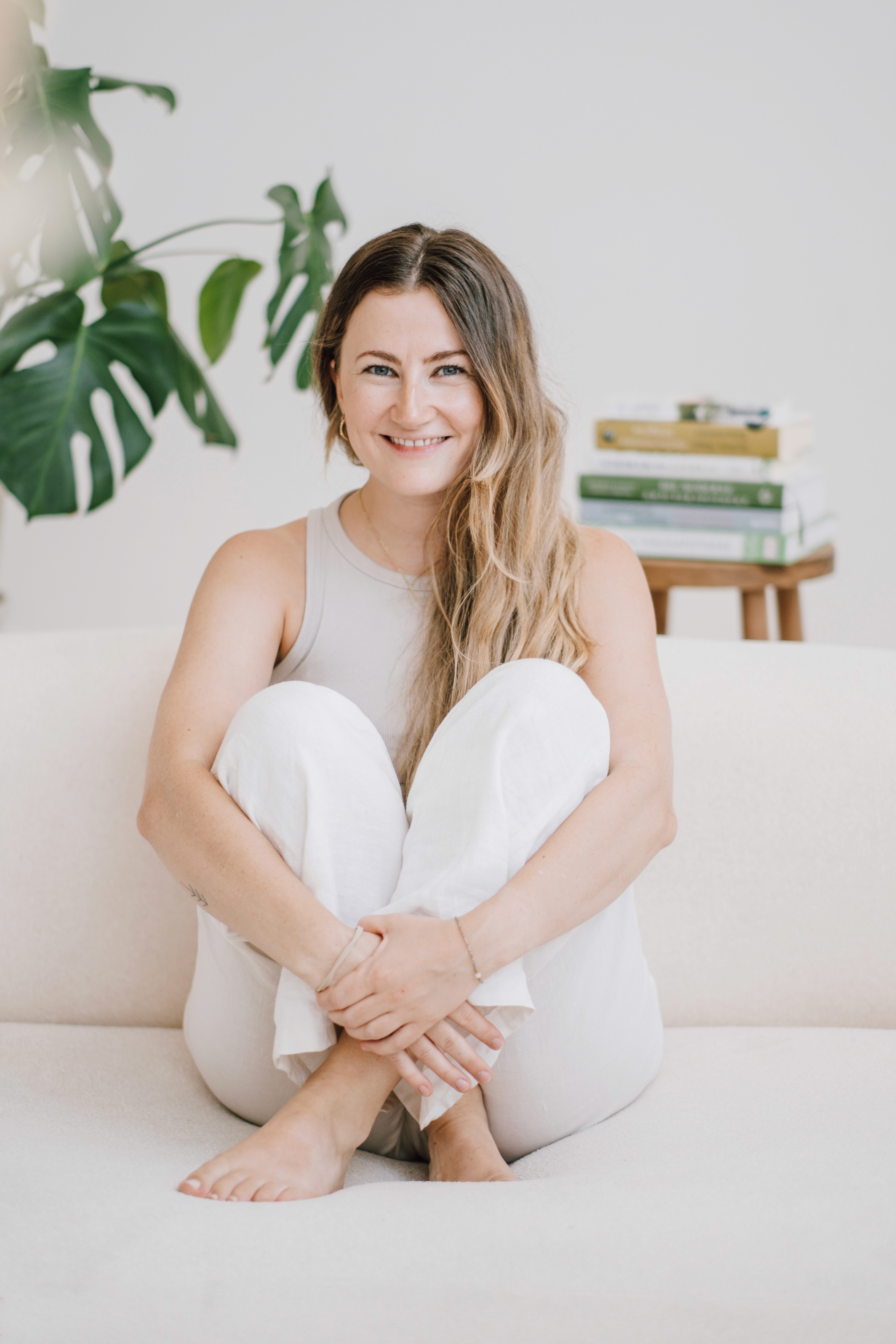 Antonia sitzt auf weißer Couch mit Knien angezogen