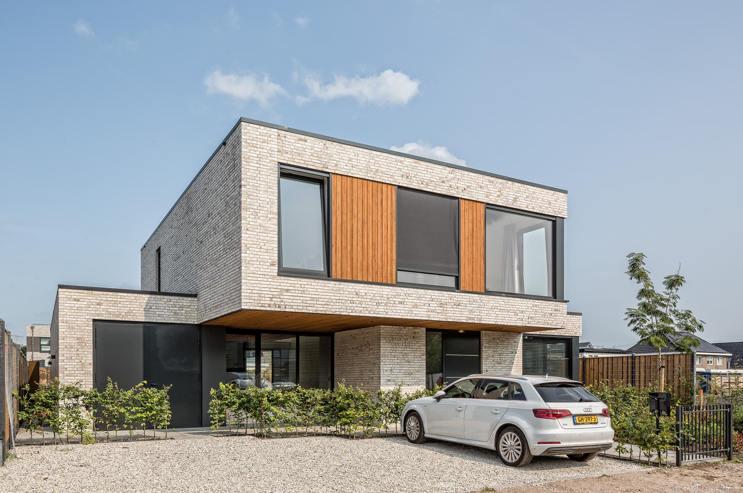 Moderne villa in Zonnehoeve Apeldoorn met lichte bakstenen gevel, grote glaspartijen en groene voortuin