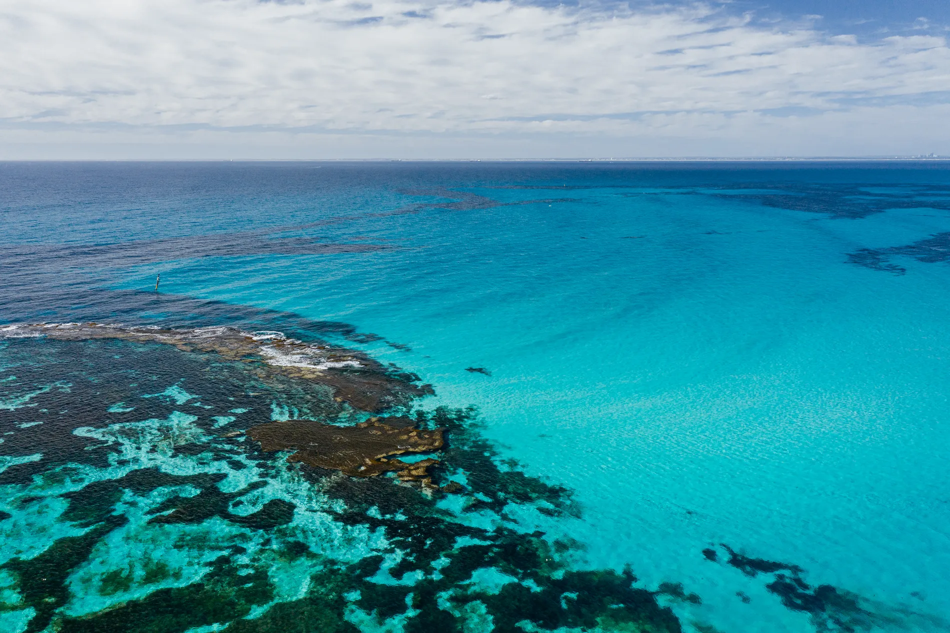 Aerial of a reef edge where deep blue water shelves into bright turquoise