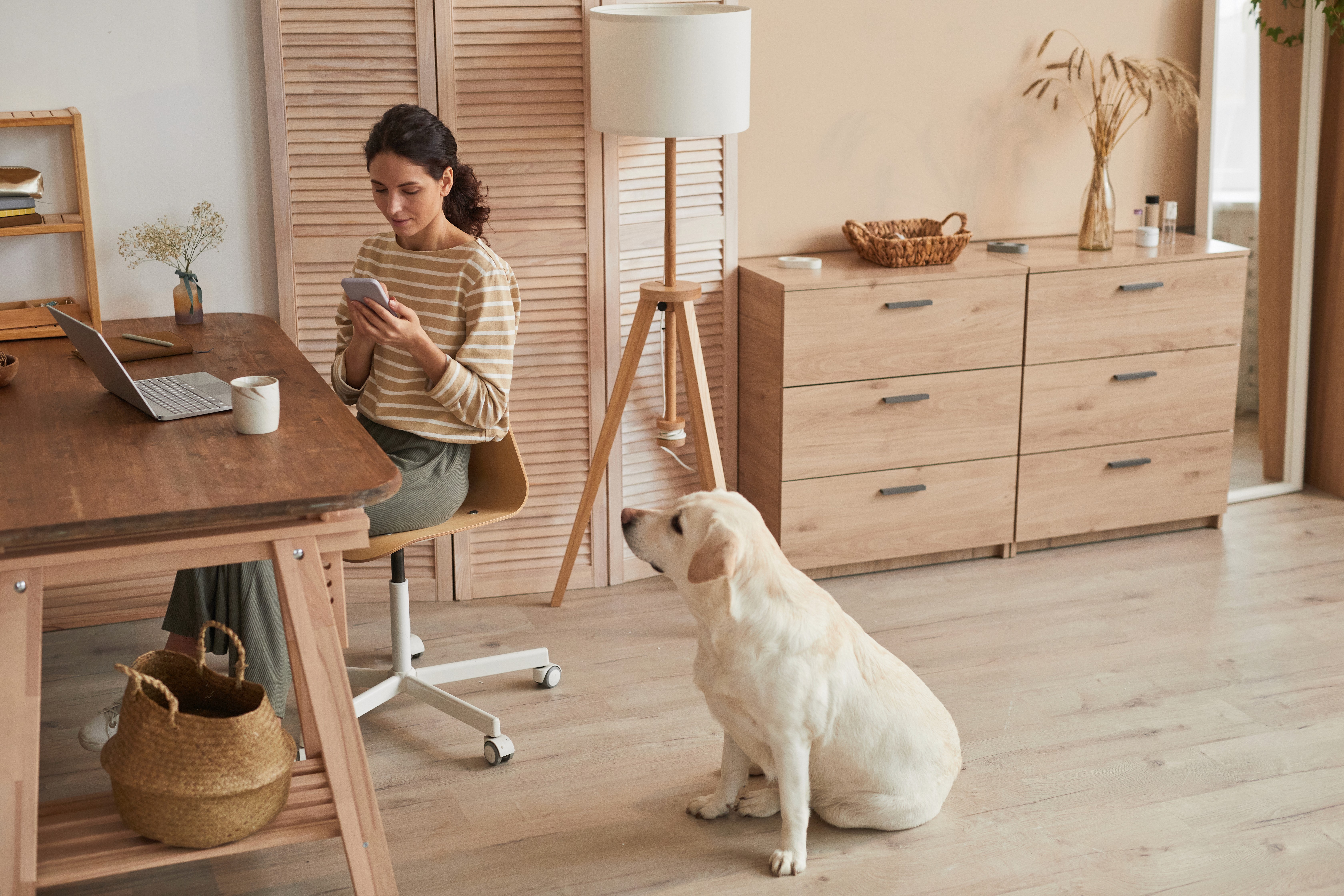 A woman works comfortably from home while her dog sits beside her on LUXO’s light wood-look hybrid flooring. The durable, pet-friendly surface supports modern Brisbane lifestyles, offering scratch resistance, easy cleaning, and a warm, natural finish ideal for Australian homes.