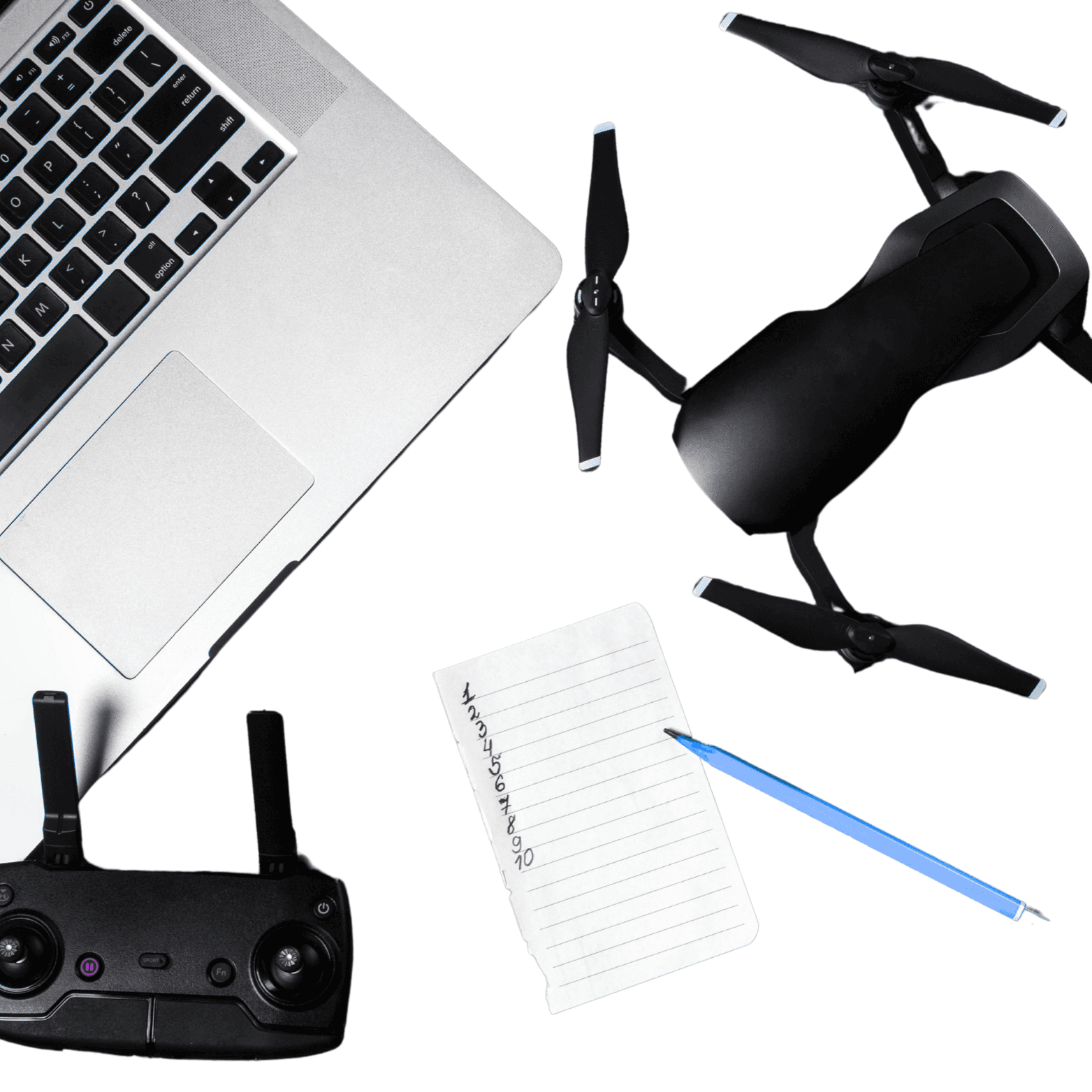 A white desk showing a black drone, a blue pencil, a black drone controller, a small notebook and a Macbook.
