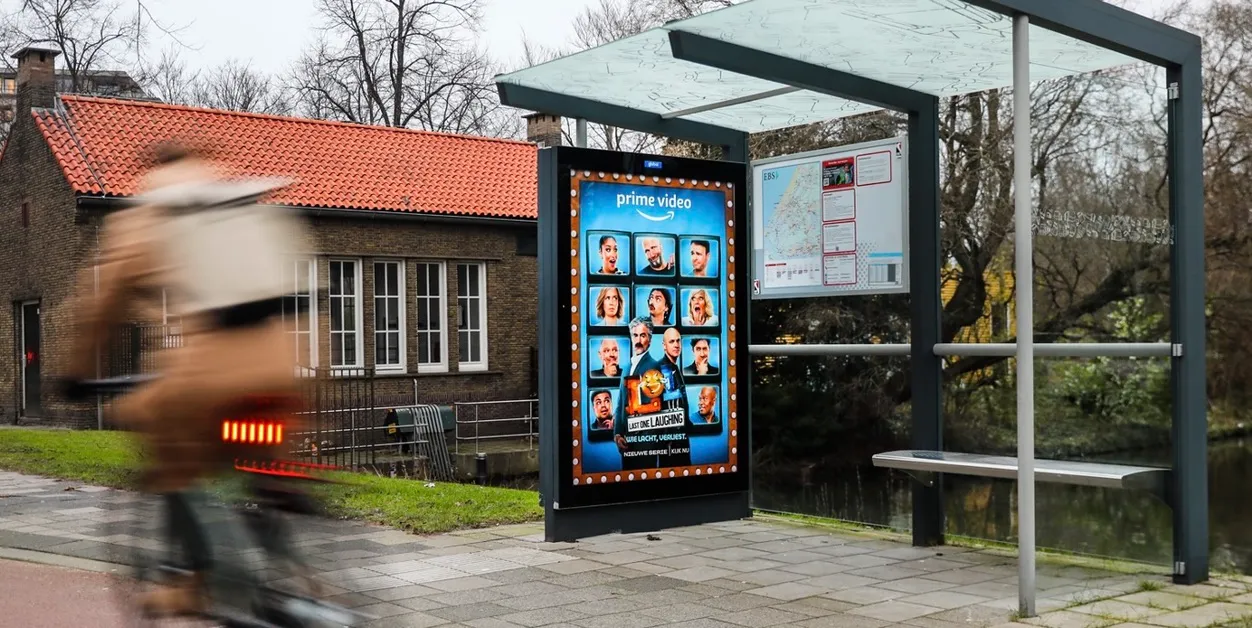 a man walking down a street past a large poster
