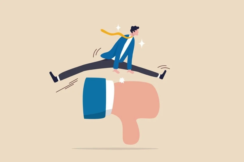 A stylized man in business attire is jumping over a thumbs-down ("dislike") icon. The image suggests overcoming criticism or failure.