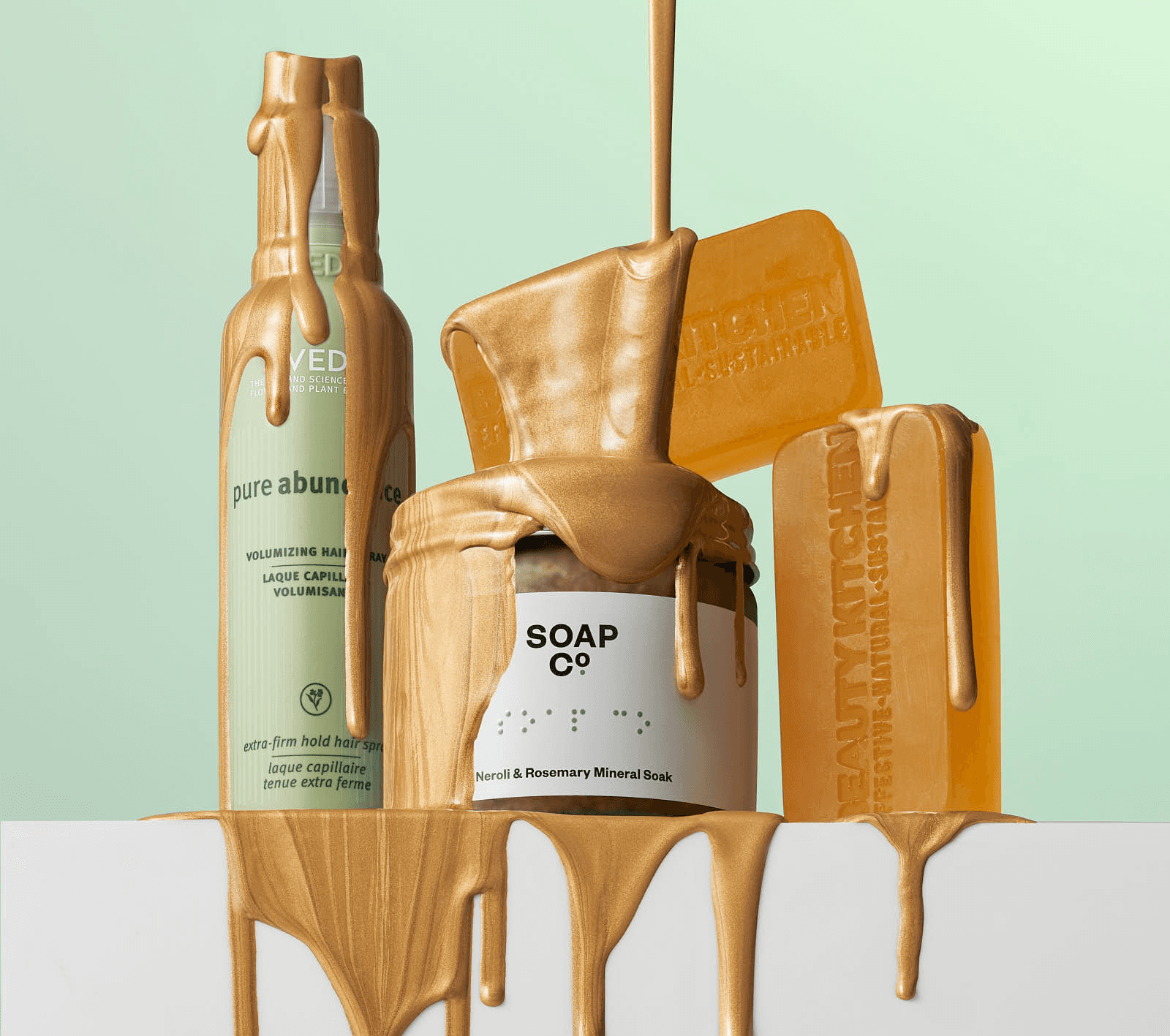 Three skincare products are artistically arranged, with golden liquid dripping from them against a light green backdrop.