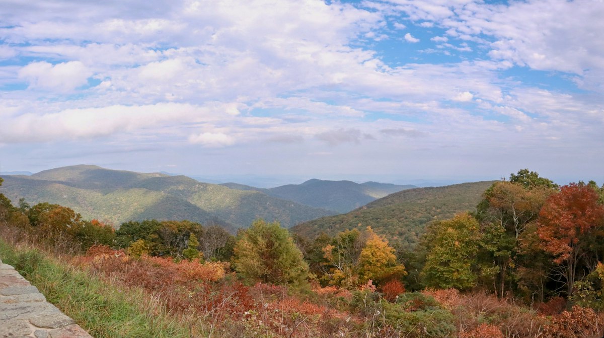 Stone-walled overlook looking across forested ridges turning orange and red