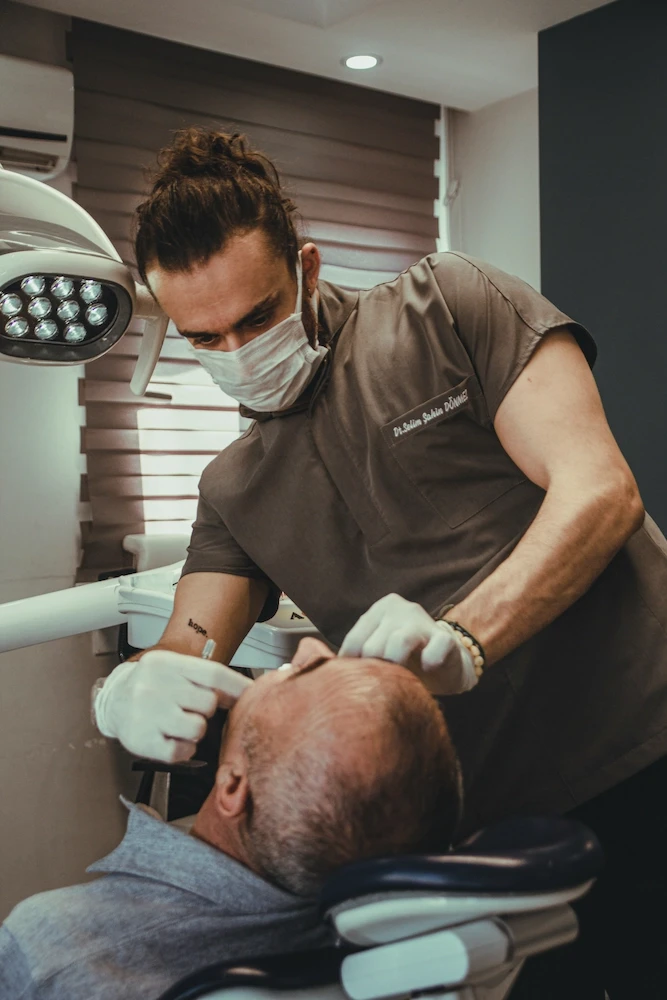 Male patient in chair and male dentist inspecting the situation with the lamp on