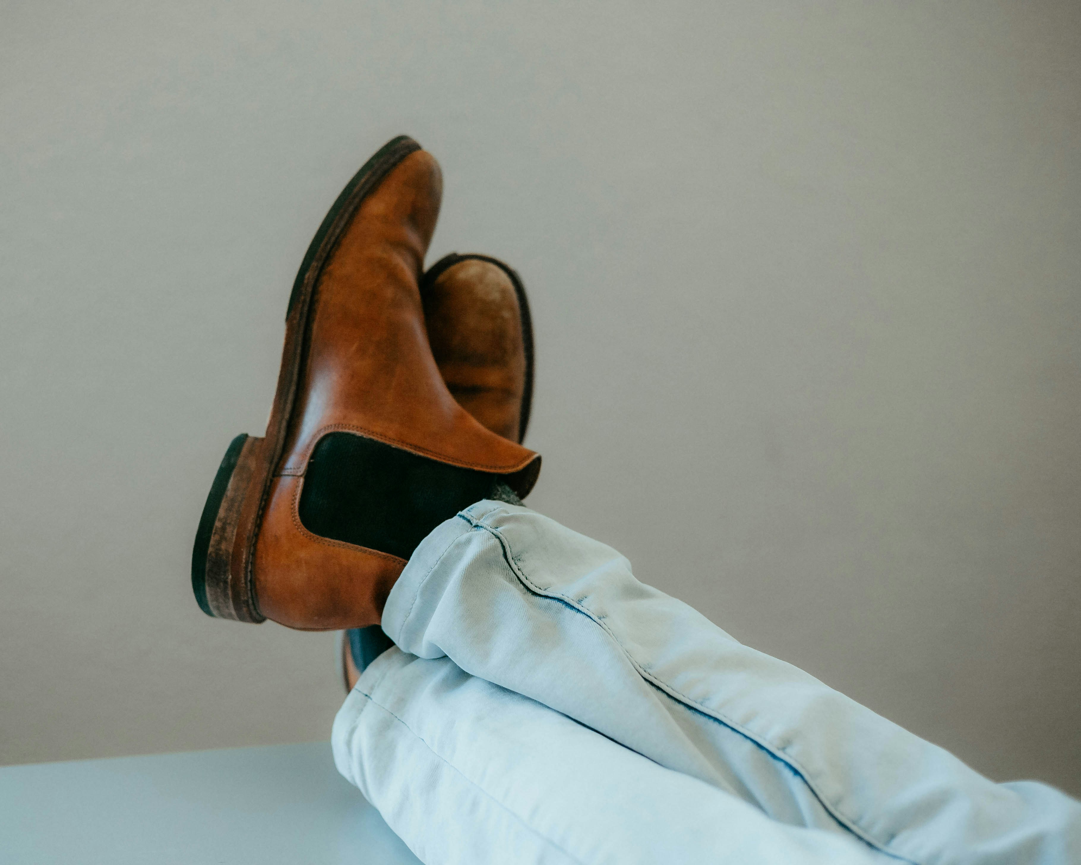 person in white pants wearing brown leather shoes