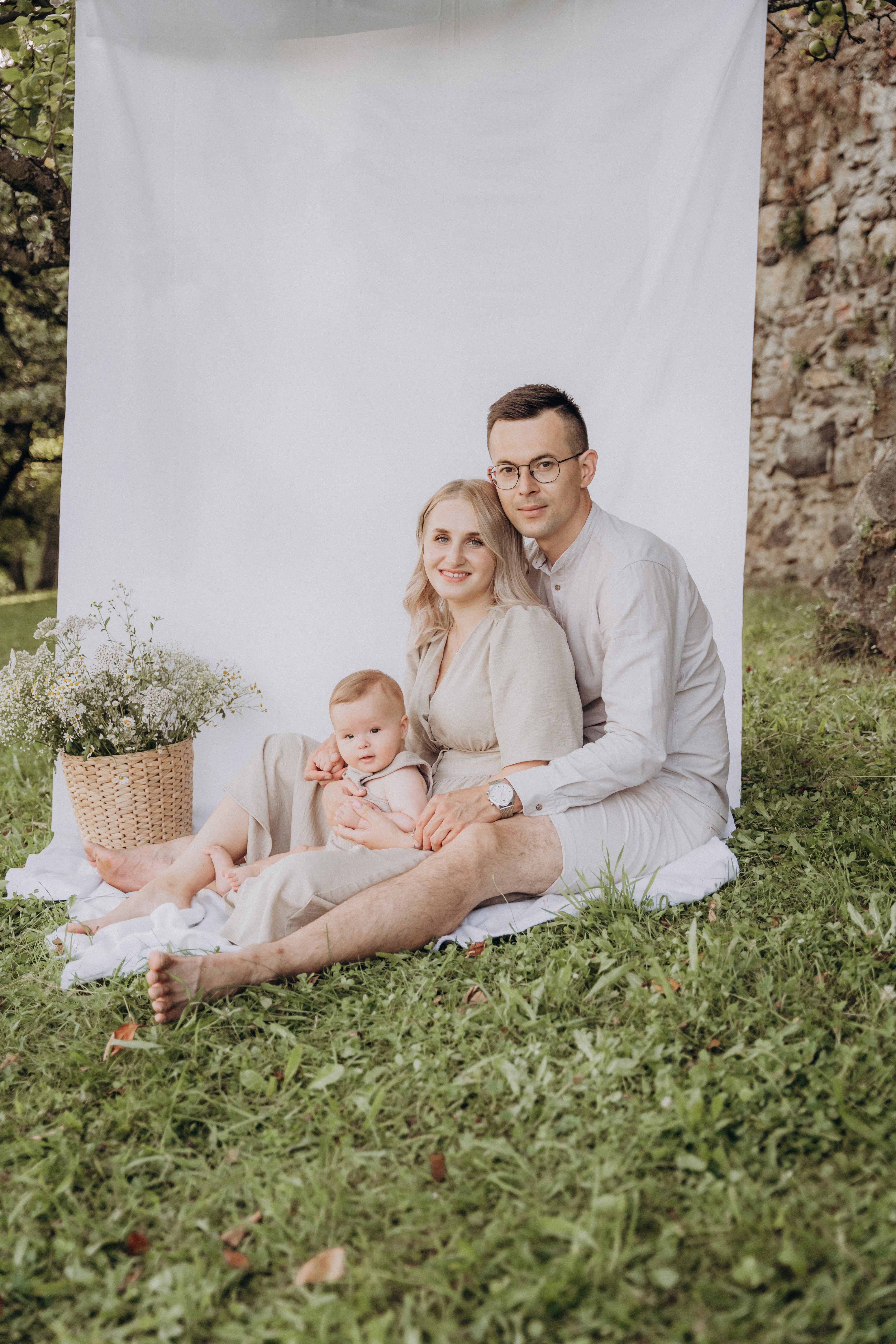 Familienfotografie in Bogen, Niederbayern – Eltern sitzen mit ihrem Baby im Grünen beim Outdoor Fotoshooting.