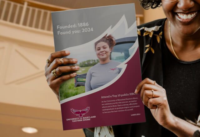 A person holds a University of Maryland Eastern Shore brochure featuring a student, school logo, and text highlighting the university’s founding year and ranking.