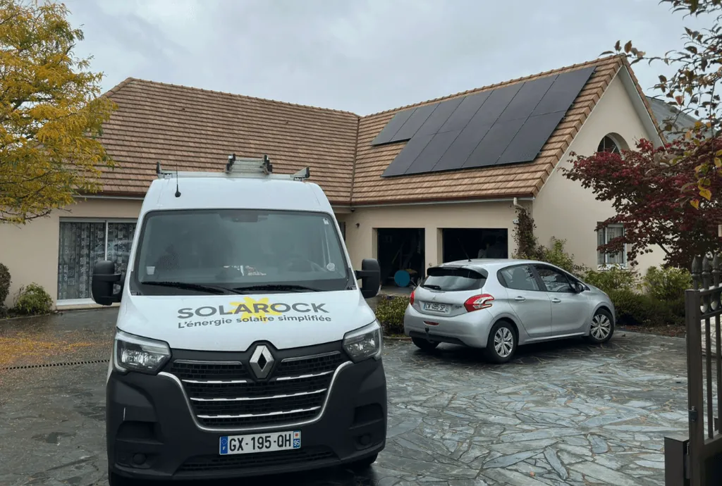 Photo d'une maison en arrière plan équipe de panneaux solaires dont l'installation a été faite par la société Solarock. On voit d'ailleurs le camion Solarock en premier plan
