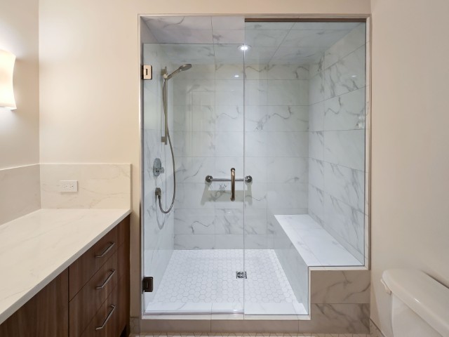 Image of KHD Homes primary ensuite bathroom with modern glass shower enclosure and marble tile design elements.