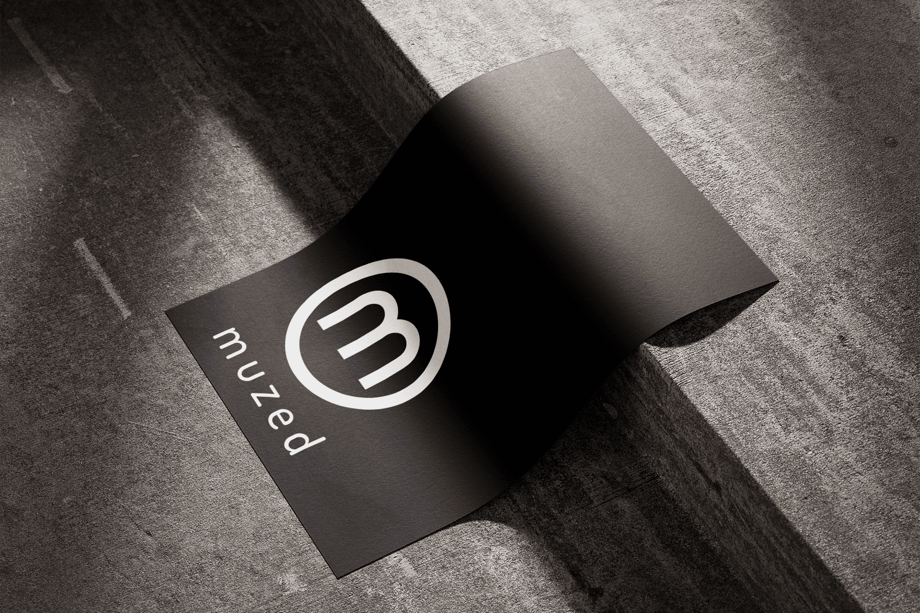 Muzed brand identity on a black sheet of paper