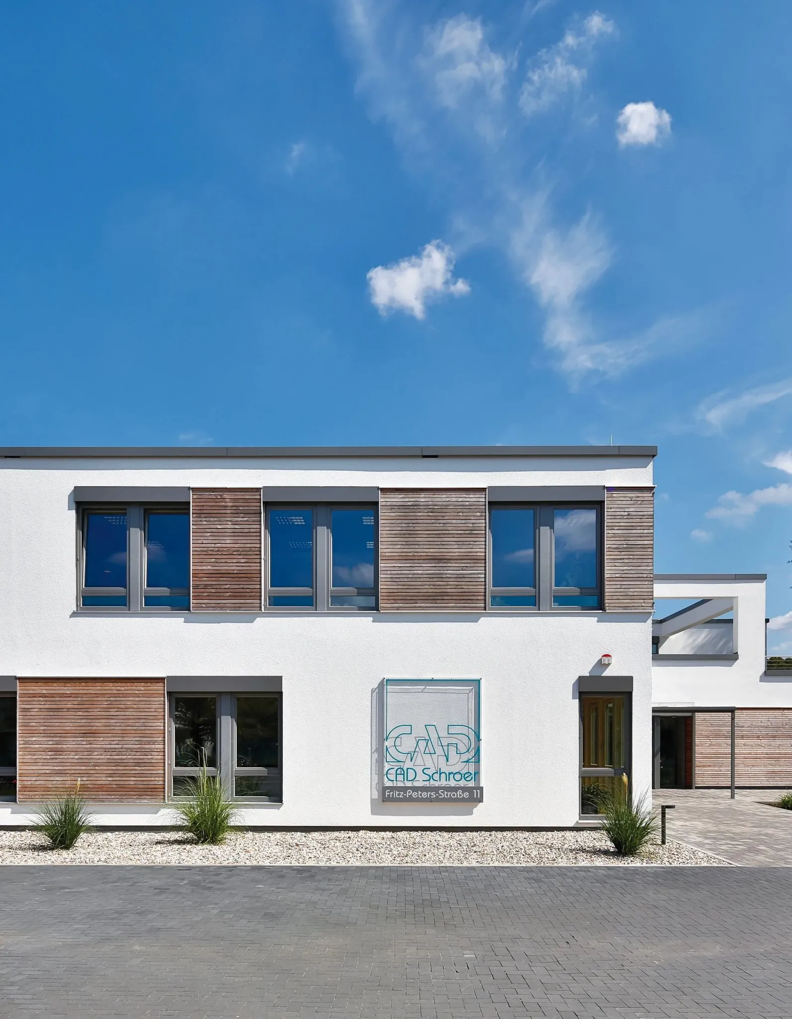 Moderne Bürogebäude mit Holzakzenten und blauem Himmel, Beschriftung CAD Schroer, Fritz-Peters-Straße 11