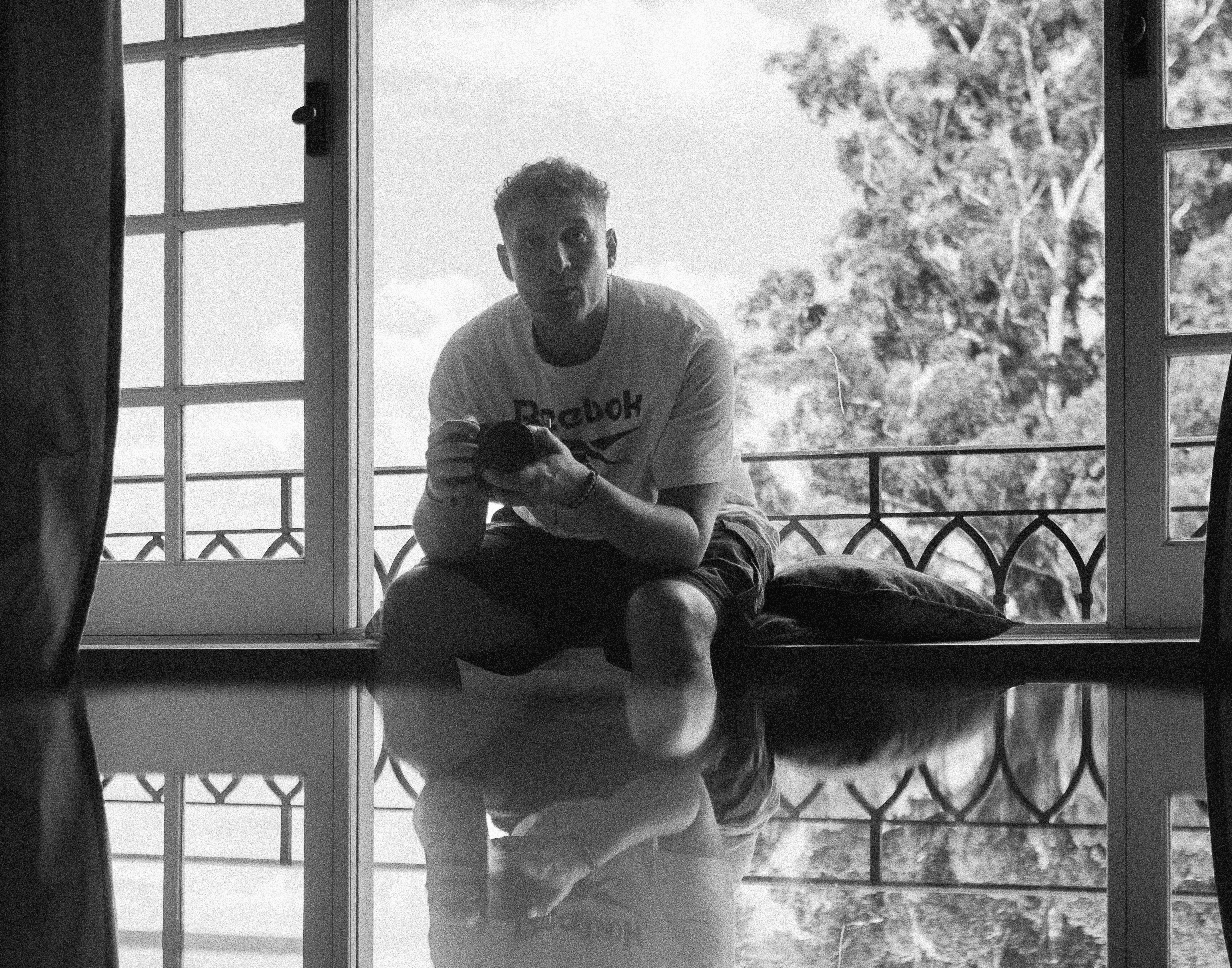 A thoughtful young person with dark hair gazes to the side, captured in soft black and white lighting.