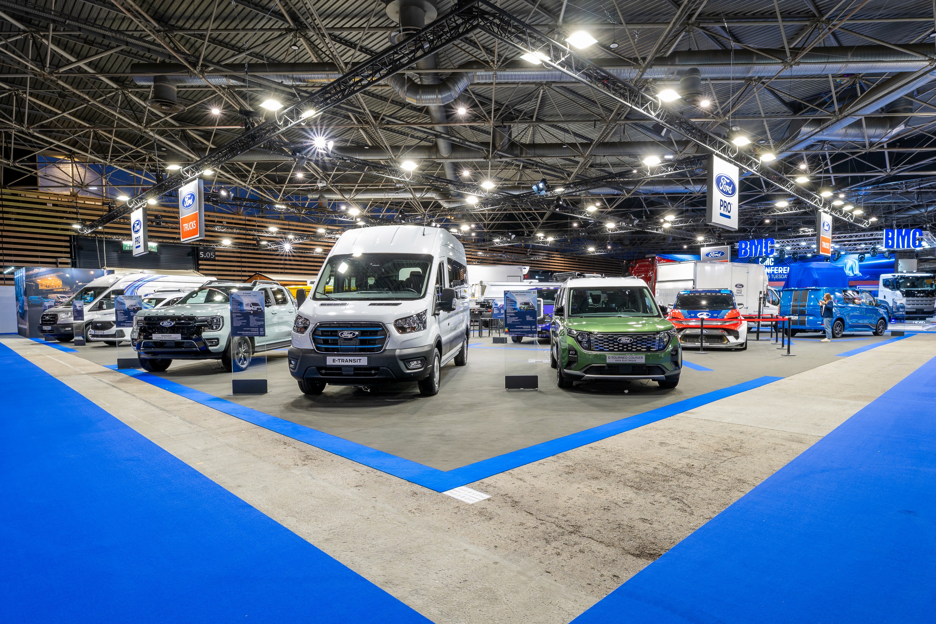 Stand Ford Trucks Solutrans Lyon 2026 conçu par Expace – vue d'ensemble du stand avec allée centrale sol bleu, camions en exposition et ambiance salon professionnel transport