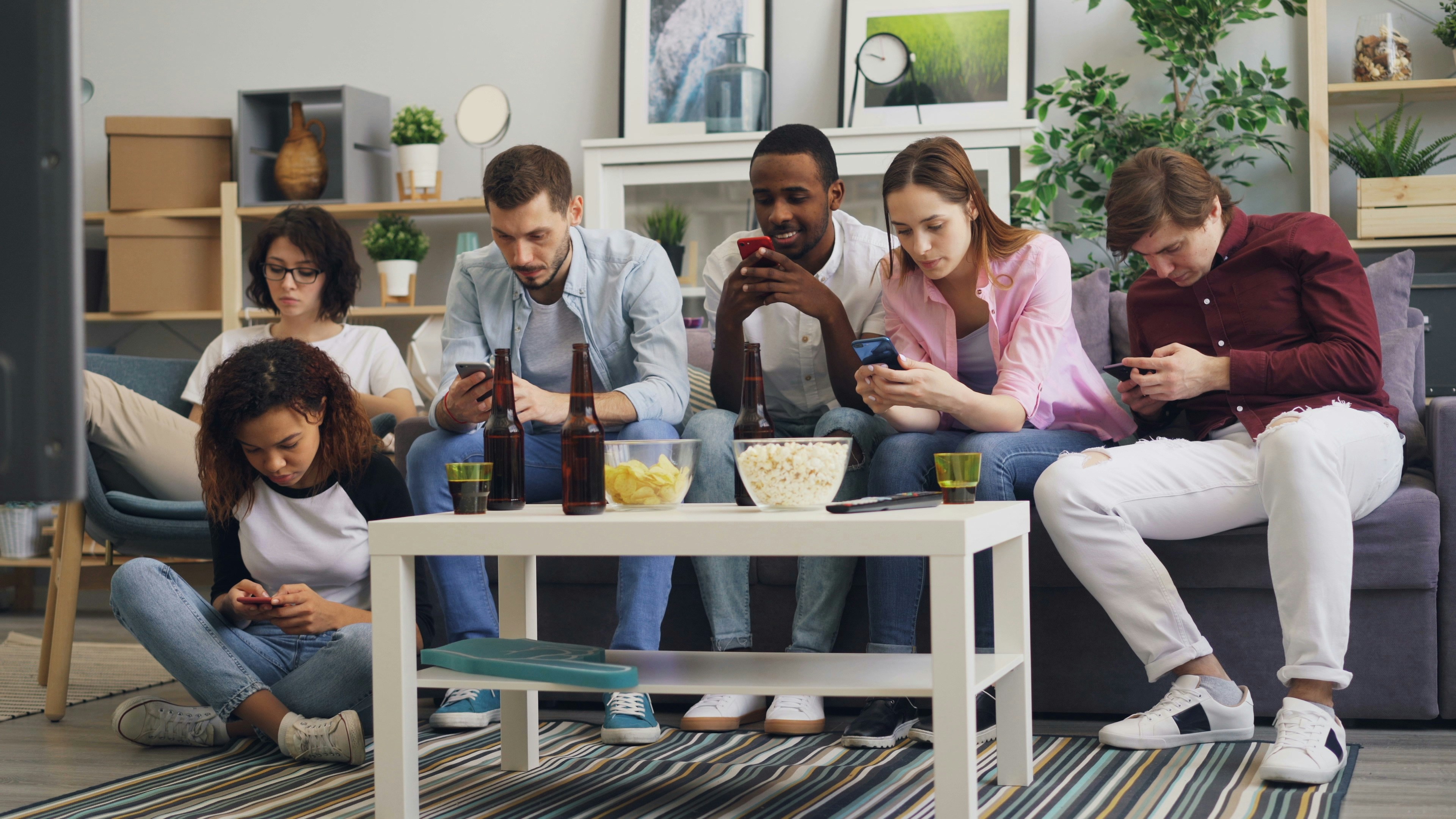 a group of people sitting on a couch looking at their phones