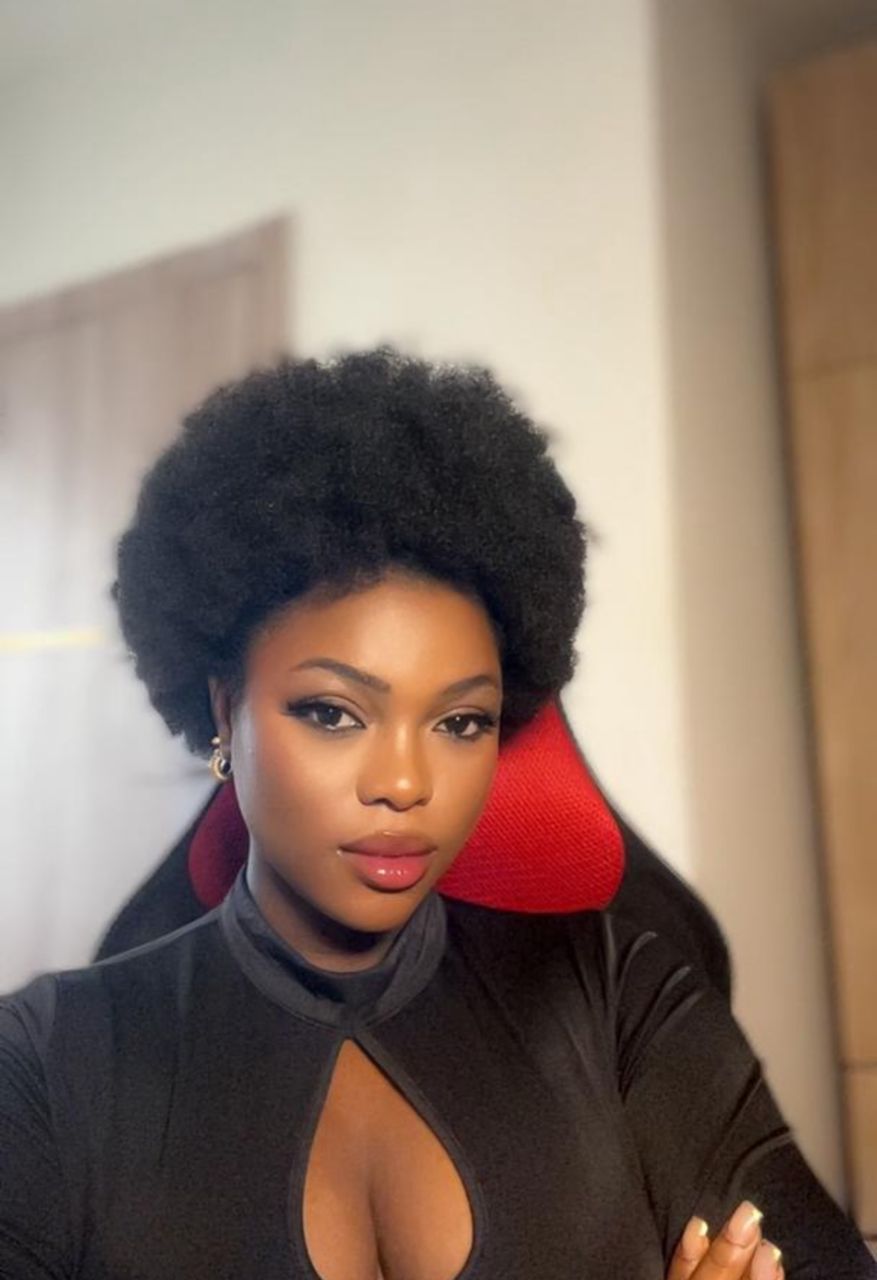 african girl in black seated on a red chair