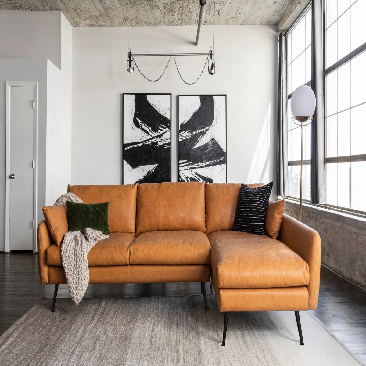 Camel-leathered Albany Park 114" mid-century modern sofa sectional, set in an industrial-style living room.