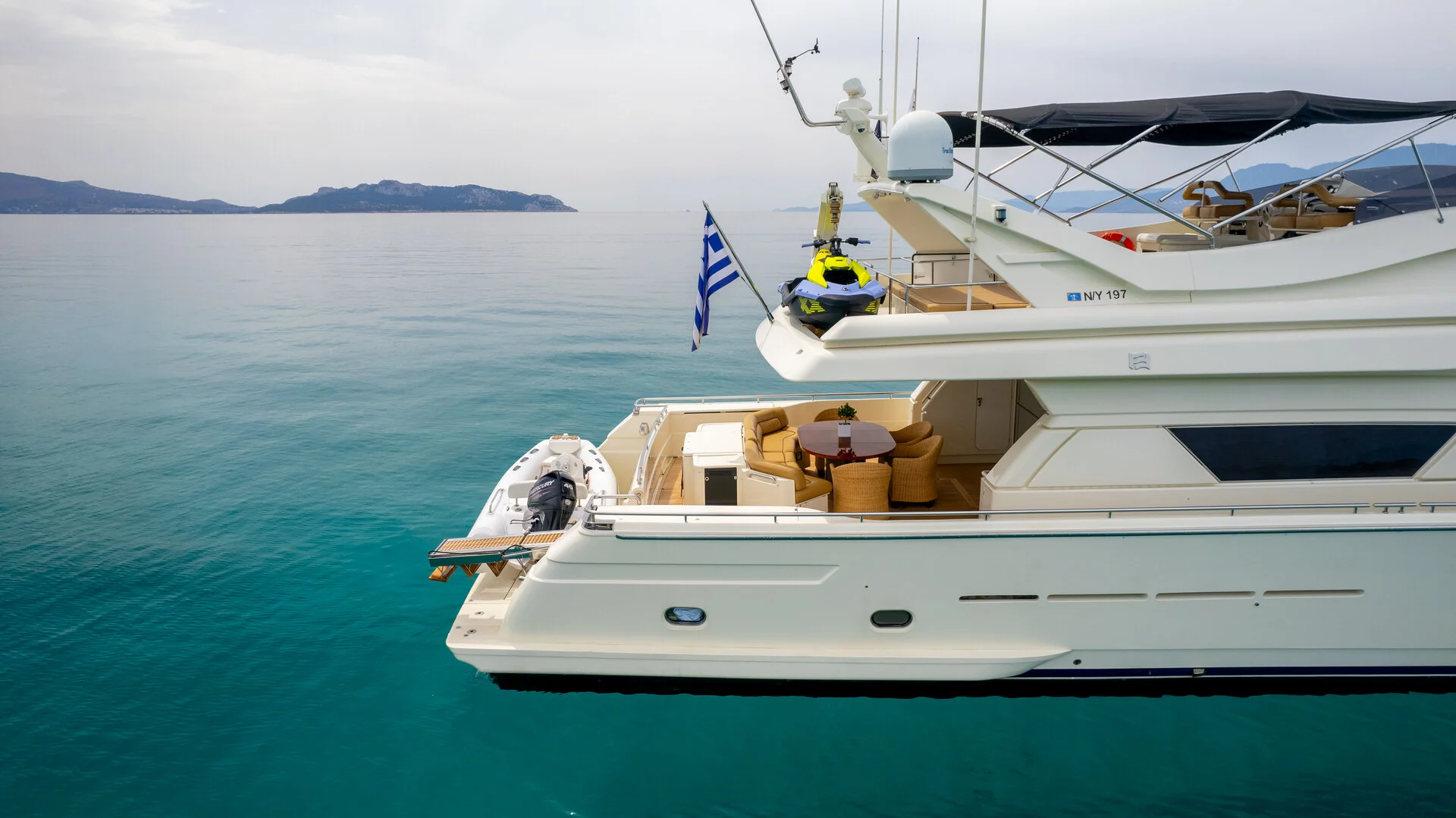 White Rock 36 speedboat with captain at helm cruising calm blue waters near Paros coastline with hills in background.