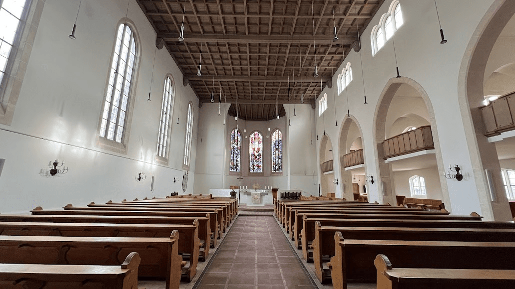 An elegant wedding ceremony setup features a domed gazebo adorned with peach and pink floral arrangements and lush greenery. White chairs line the aisle.