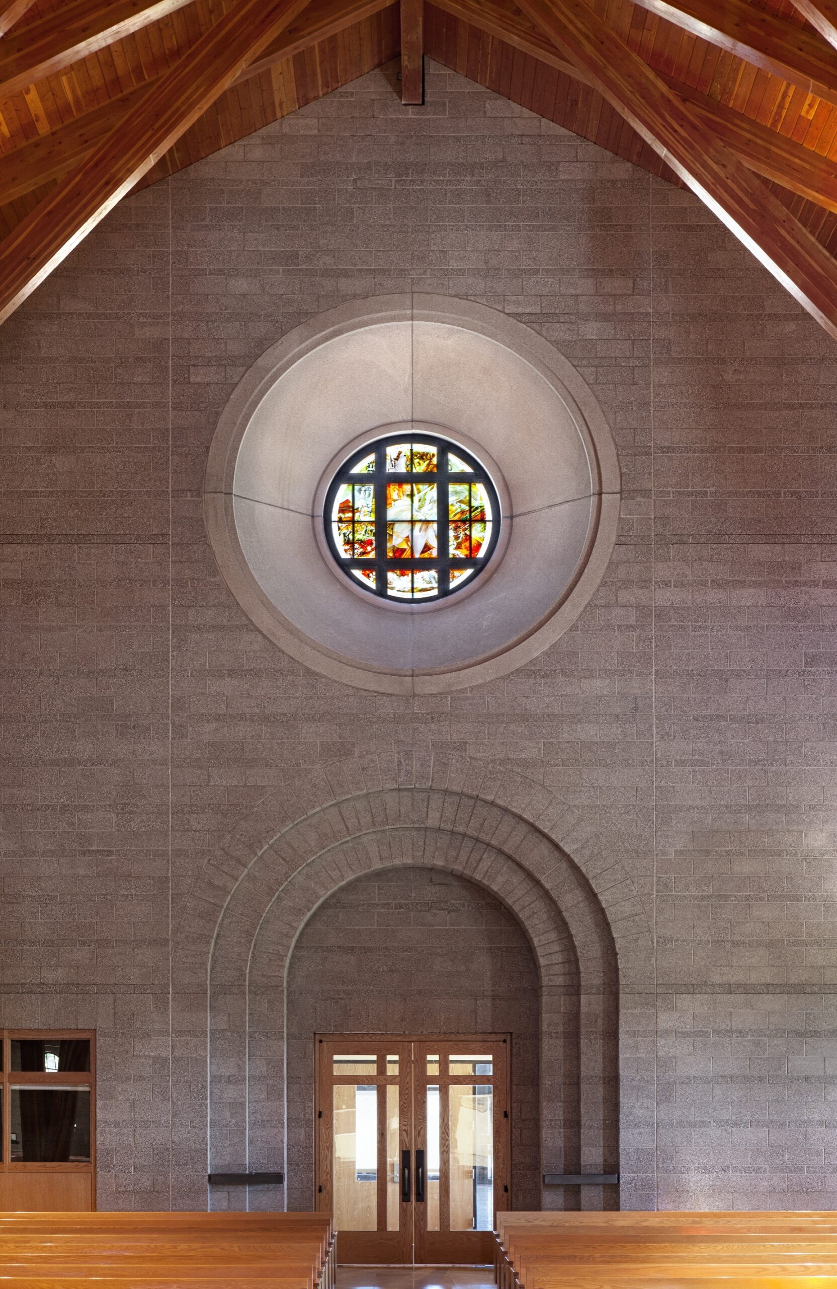 Round wedding stained glass window integrated into church architecture, part of large-scale liturgical glass commission