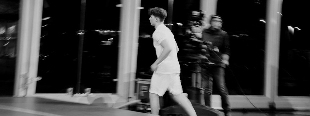 Black-and-white shot of an athlete running past during a live televised event