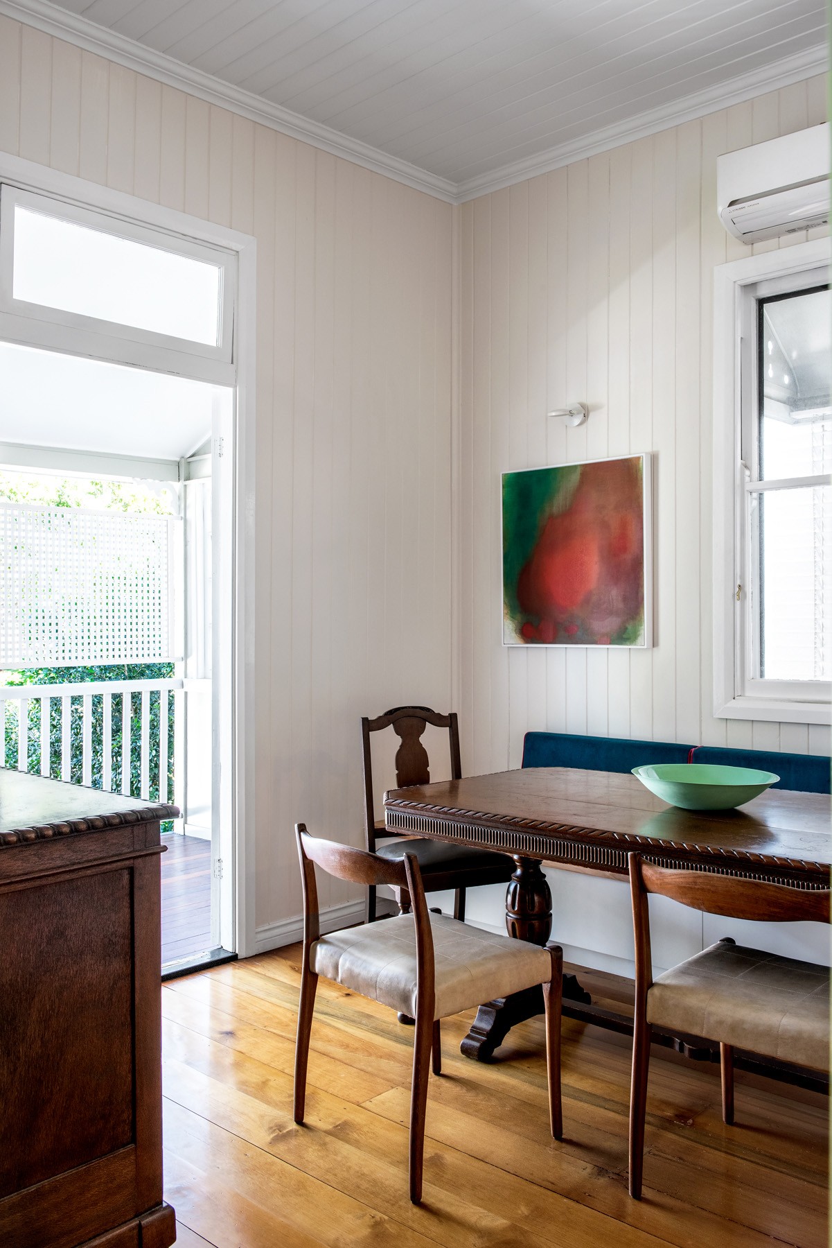 Dining space inside Oxford Cottage with timber floors, heritage joinery, and a compact table setting opening onto the front verandah.