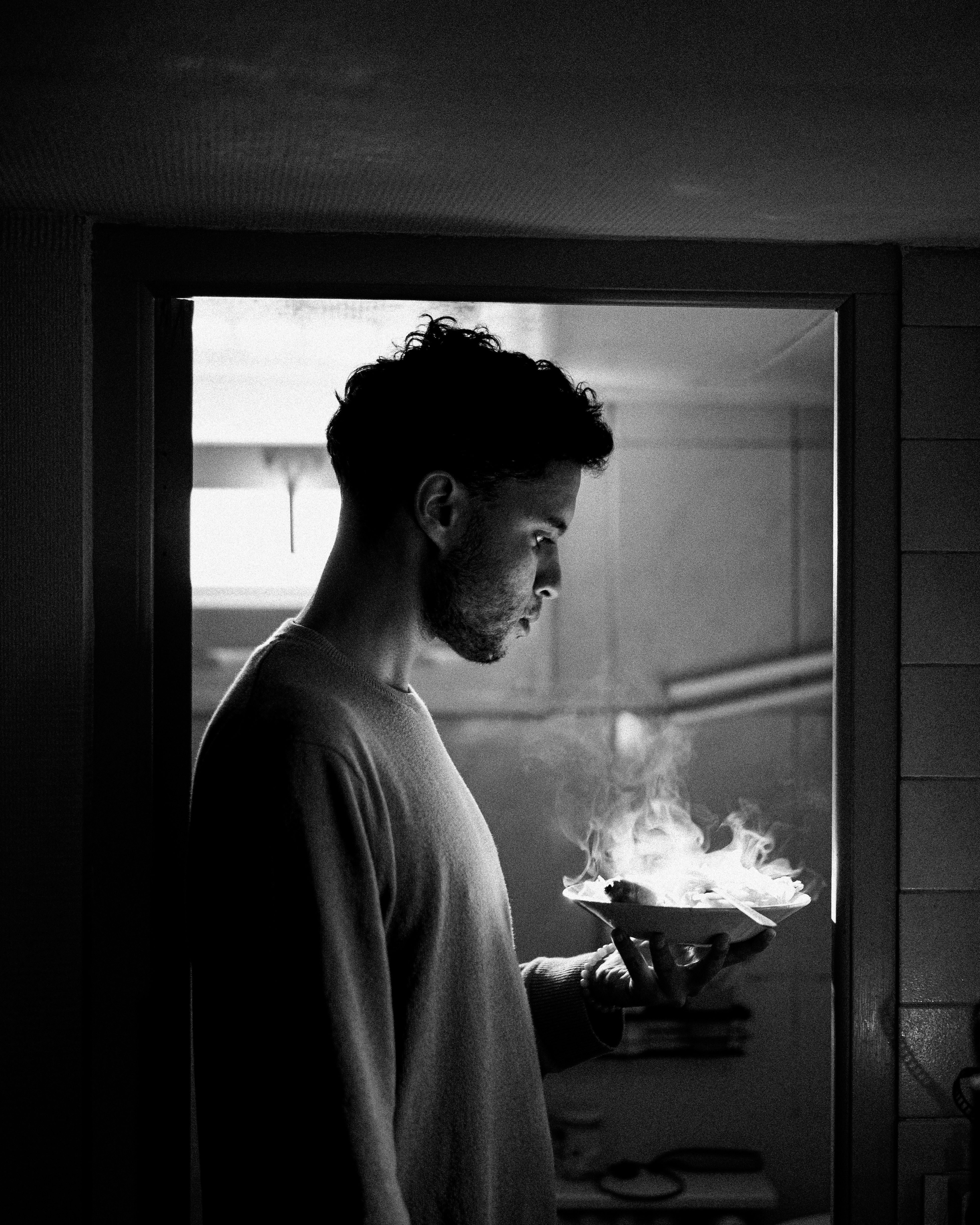 A red gondola car travels on cables over a green valley with a large lake and a town on its shore.