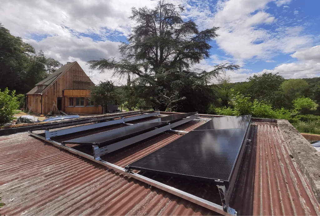 Photo de panneaux photovoltaïques DualSun qui ont été installés sur le toit d'une dépendence. On voit une maison en construction en arrière plan.