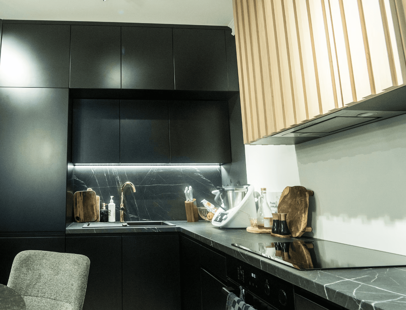 Biała kuchnia na wymiar z czarnym blatem i oświetleniem LED w Warszawie.